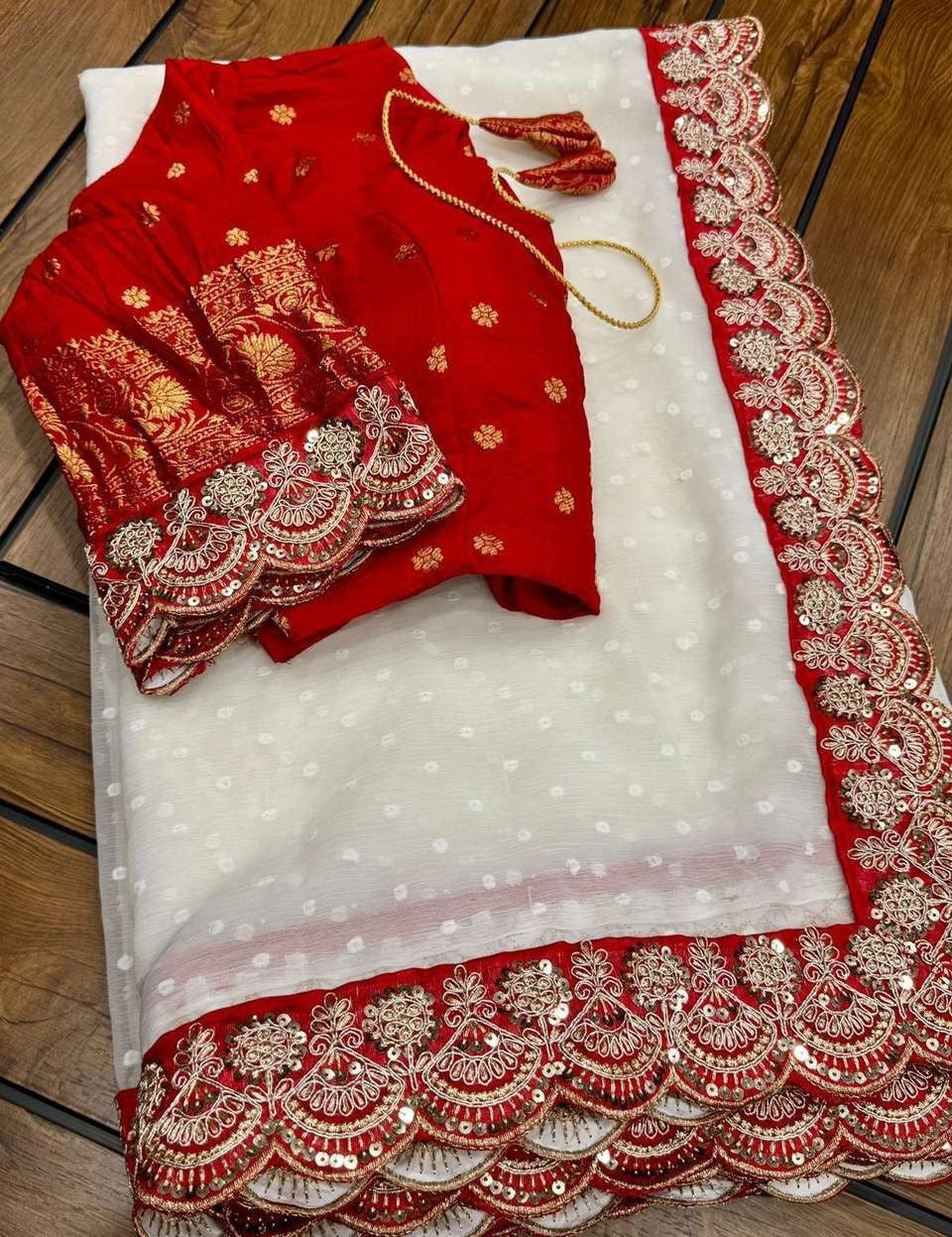 Flat-lay detail view of the ivory georgette ready-to-wear pocket saree featuring woven white polkas and a rich crimson red scalloped border with sequin embroidery.