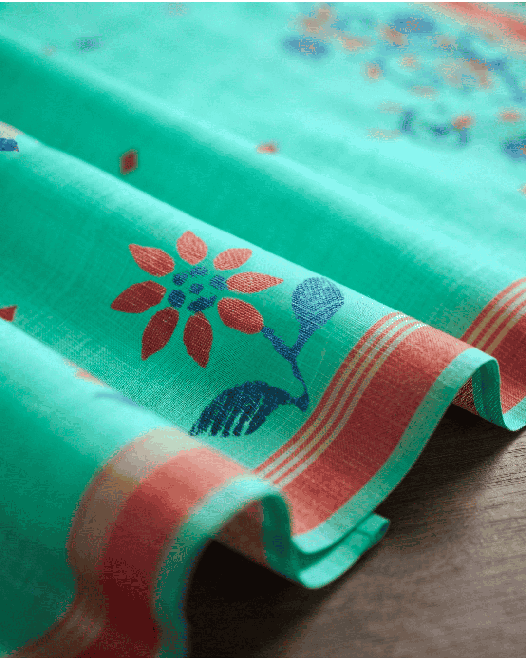 Close-up of linen pre-draped pocket saree fabric showing floral weaving in red and blue with a contrasting striped border