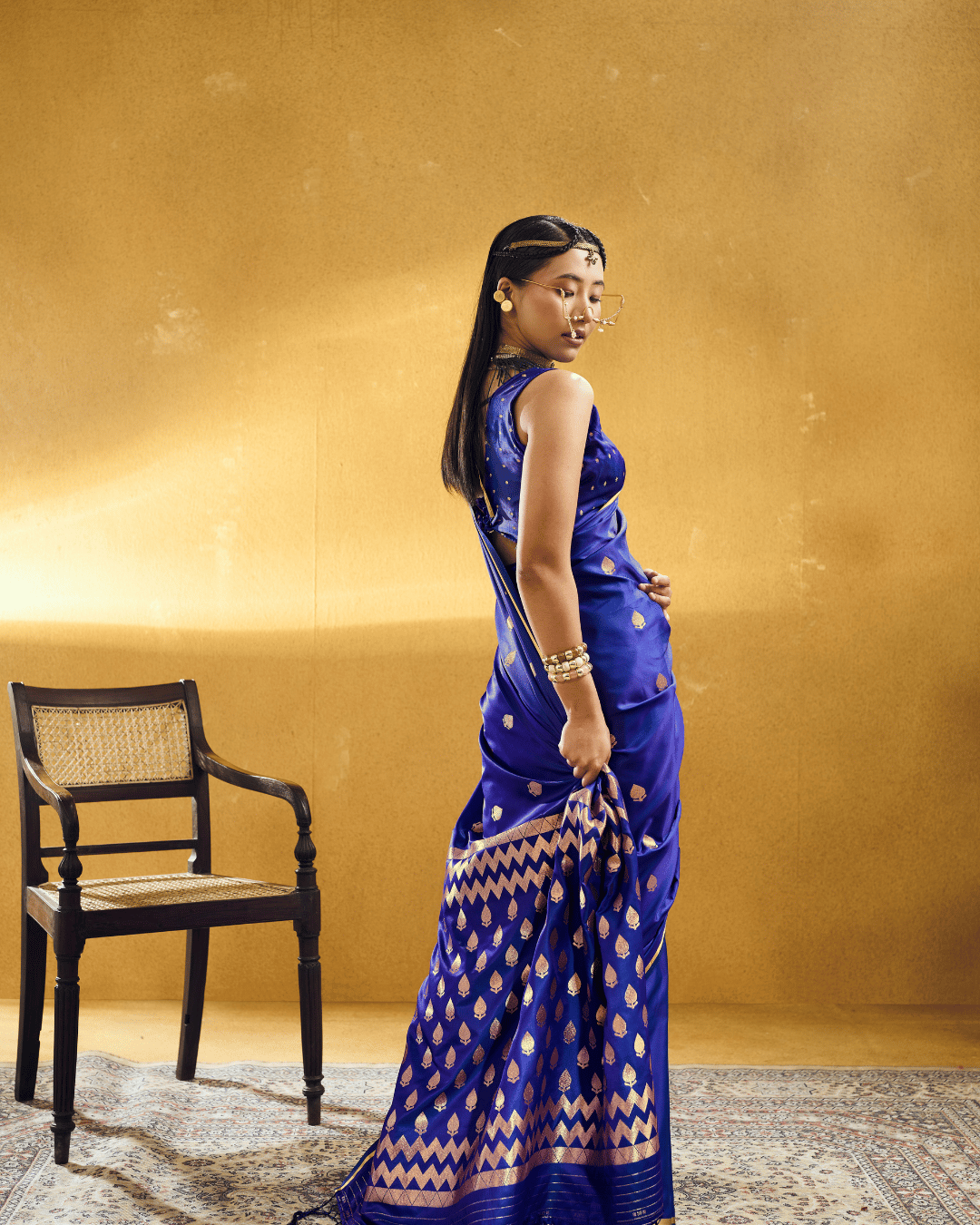 Three-quarter back-profile view showcasing the grand pallu drape of the Royal Blue Chevron ready-to-wear pocket saree, featuring dense rows of champagne-gold leaf motifs framed by multi-tiered zigzag chevron bands and dark edge tassels.