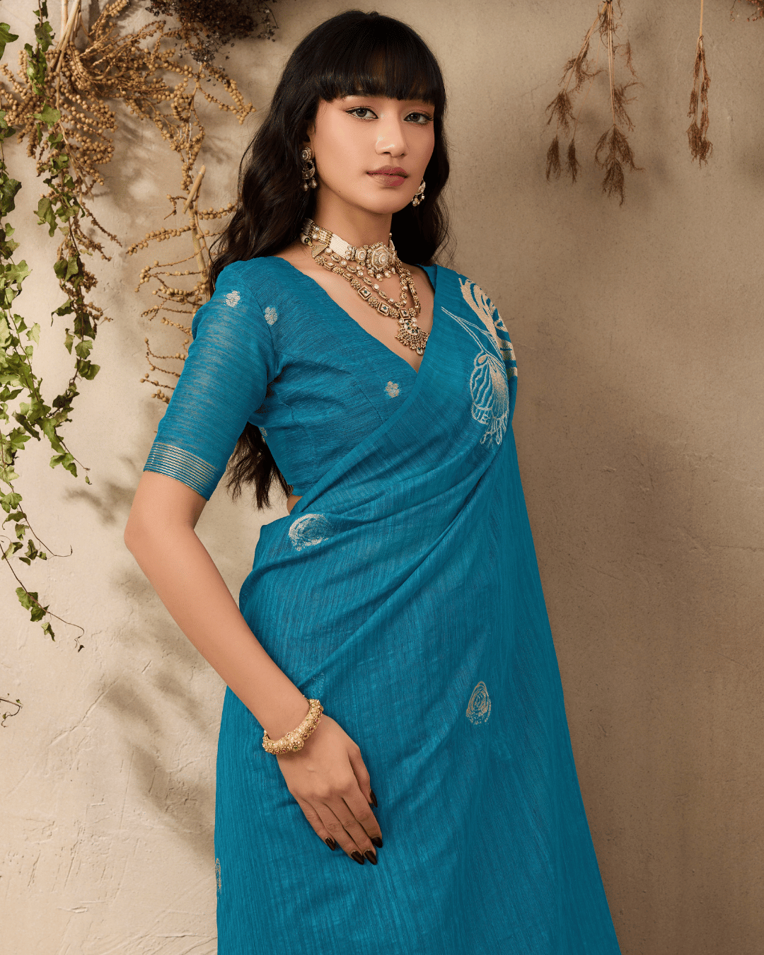 Three-quarter portrait of the model in the teal ready-to-wear pocket saree showing the soft golden line-art detailing.