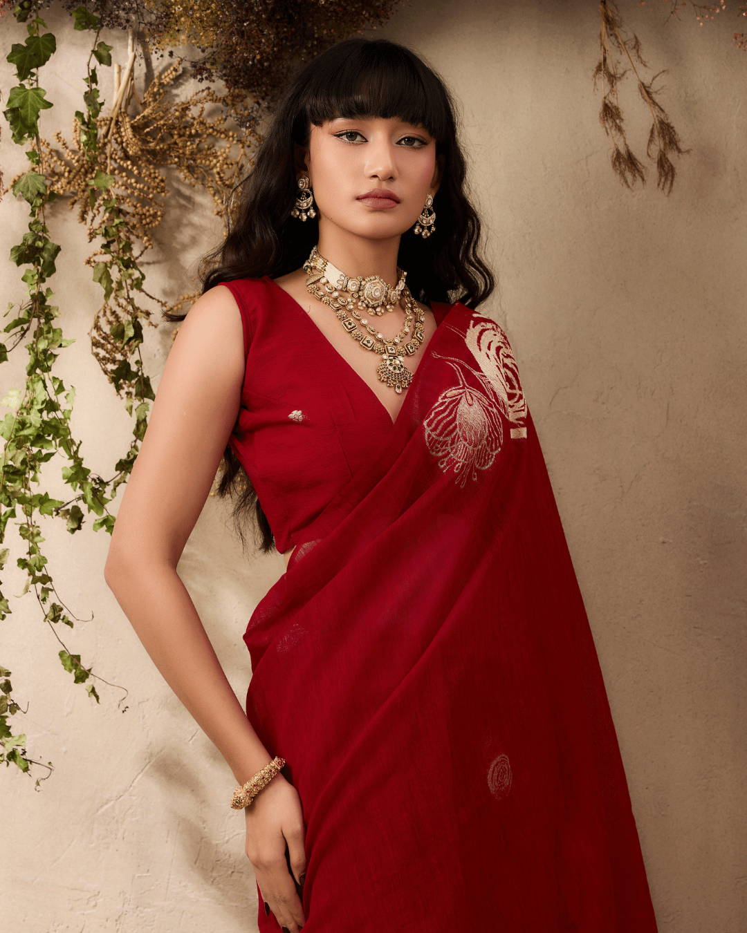 Model wearing a deep ruby-red silk ready to wear pocket saree, showcasing gold-line rose motifs.