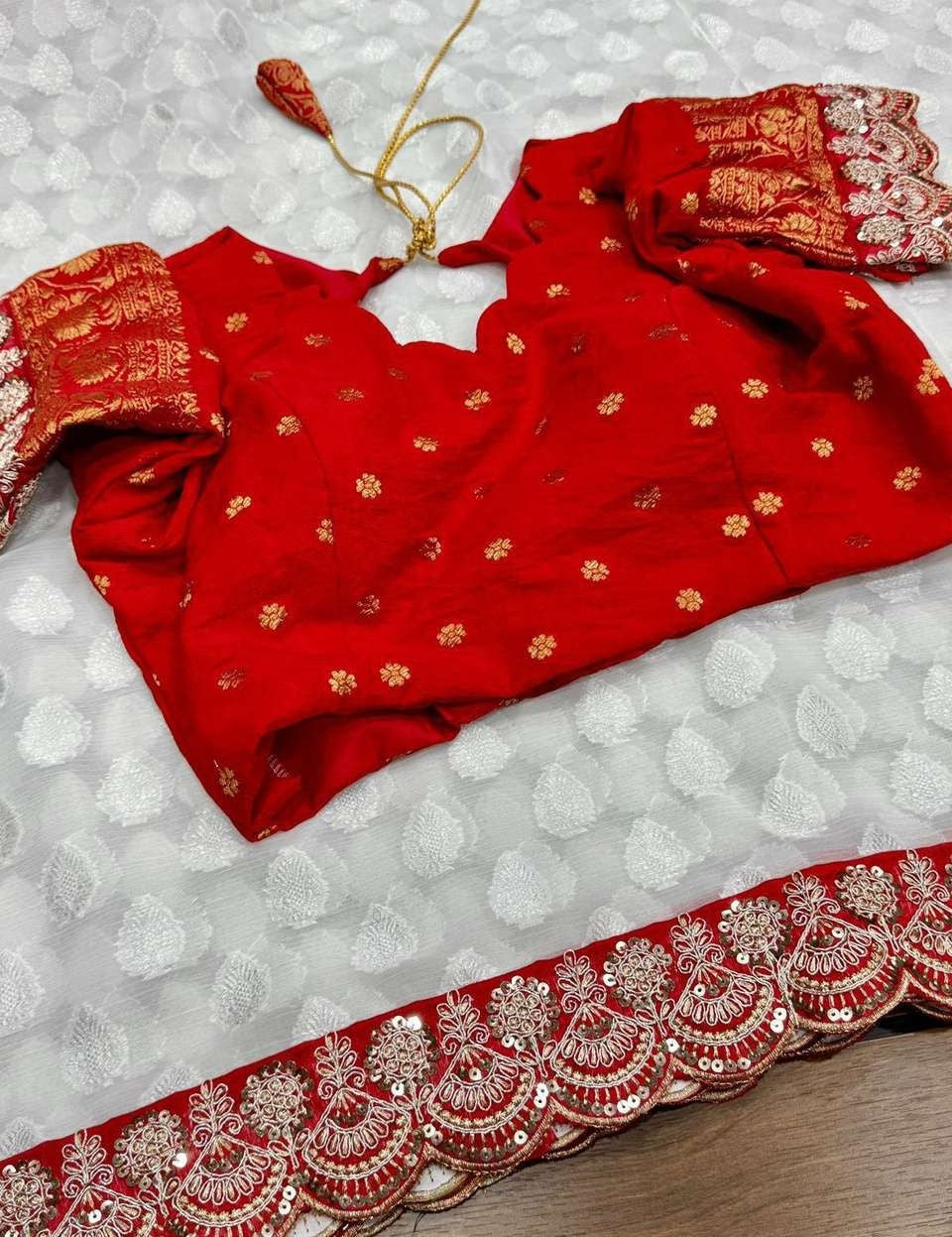 Flat-lay detail view of the ivory georgette ready-to-wear pocket saree featuring woven white leaf-shaped motifs and a rich crimson red scalloped border with sequin embroidery.