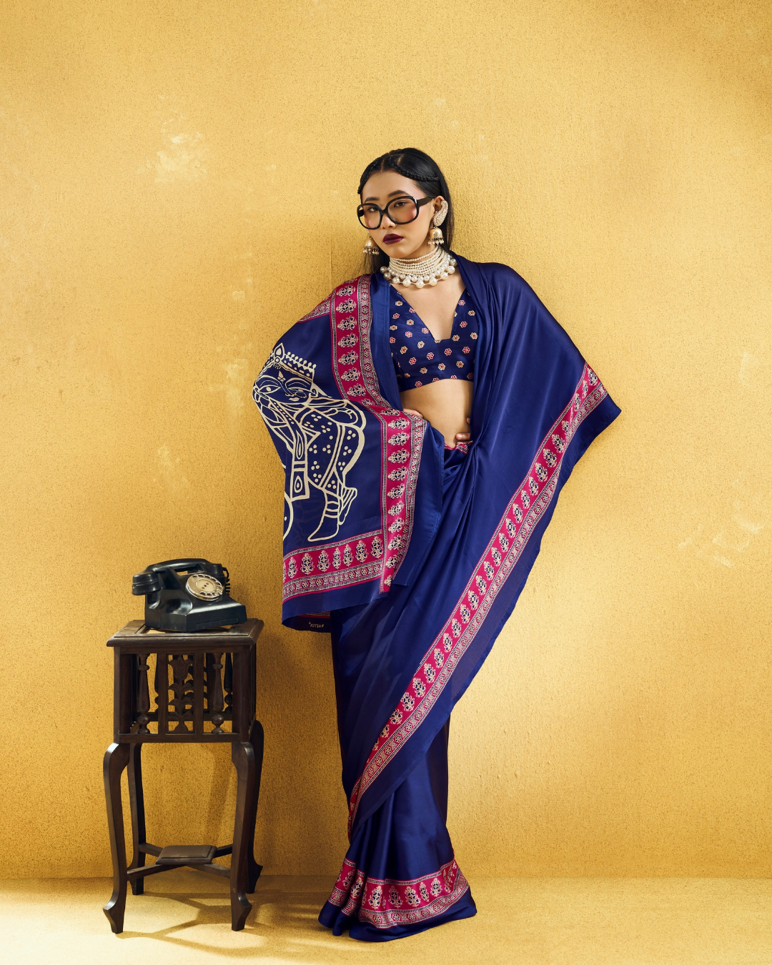 Full-length portrait of a model in a navy blue saree with magenta printed borders and a statement pallu.