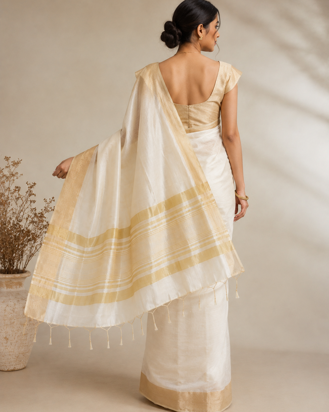 Back view of an ivory Silk Cotton ready to wear pocket saree with a soft-gold zari border and detailed striped pallu finished with delicate golden tassels.