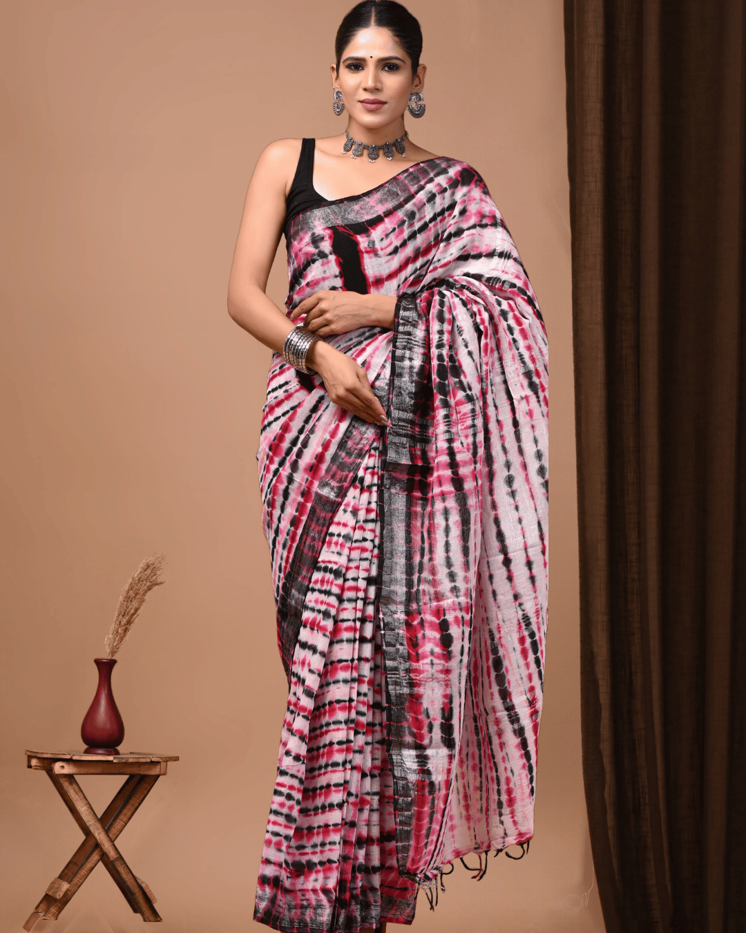 Linen Muse pink, black and red linen ready-to-wear pocket saree featuring irregular tie-dye streaks, dotted diagonal patterns, a broad charcoal border, patterned pallu and dark tassels.