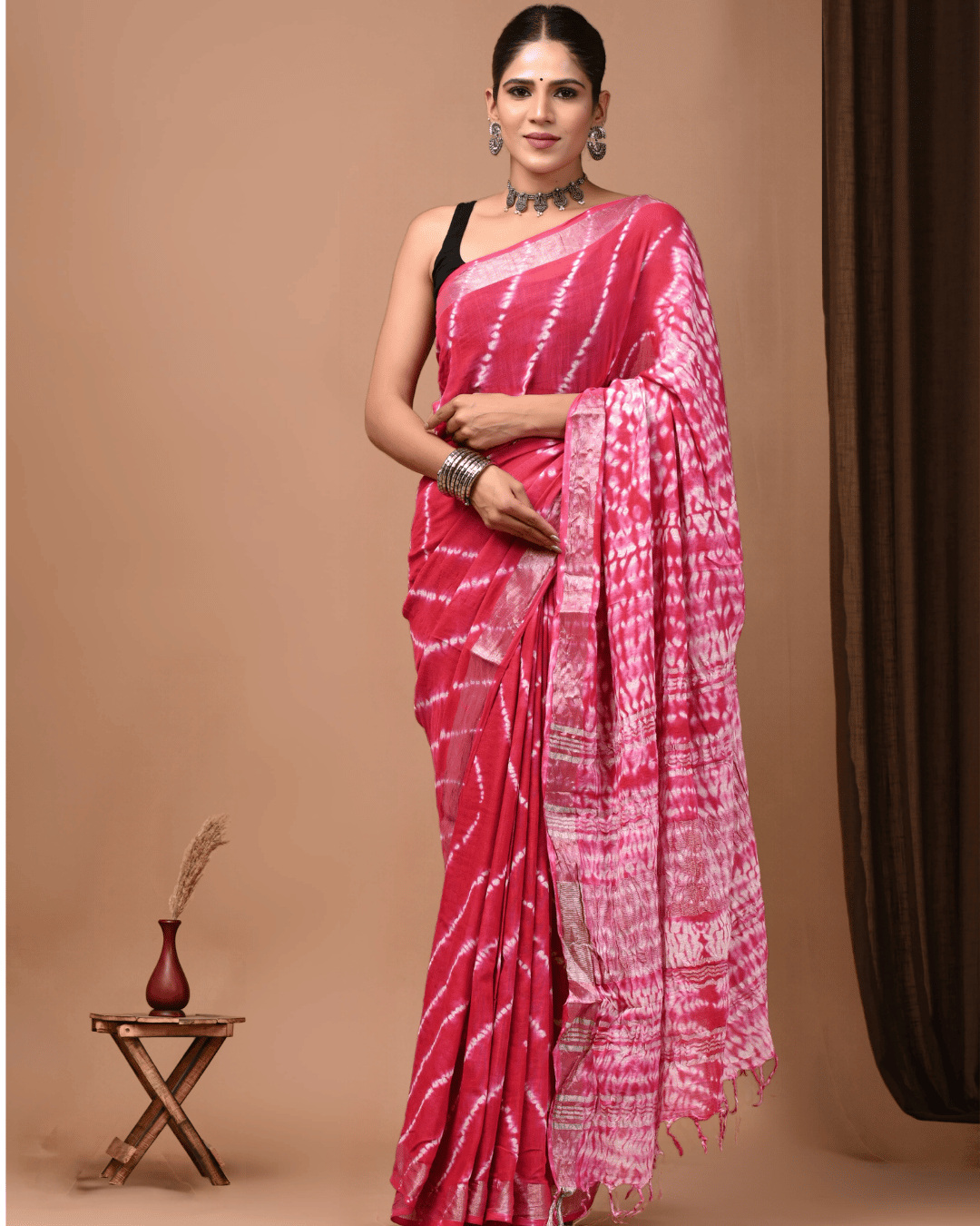 Linen Muse raspberry pink linen ready-to-wear pocket saree featuring white tie-dye patterns, a detailed pallu and tassel edging, styled for festive occasions.