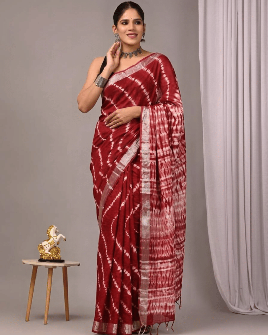Linen Muse red linen ready-to-wear pocket saree featuring ivory-white diagonal tie-dye patterns, a striped pallu, a light contrasting border and matching tassels.