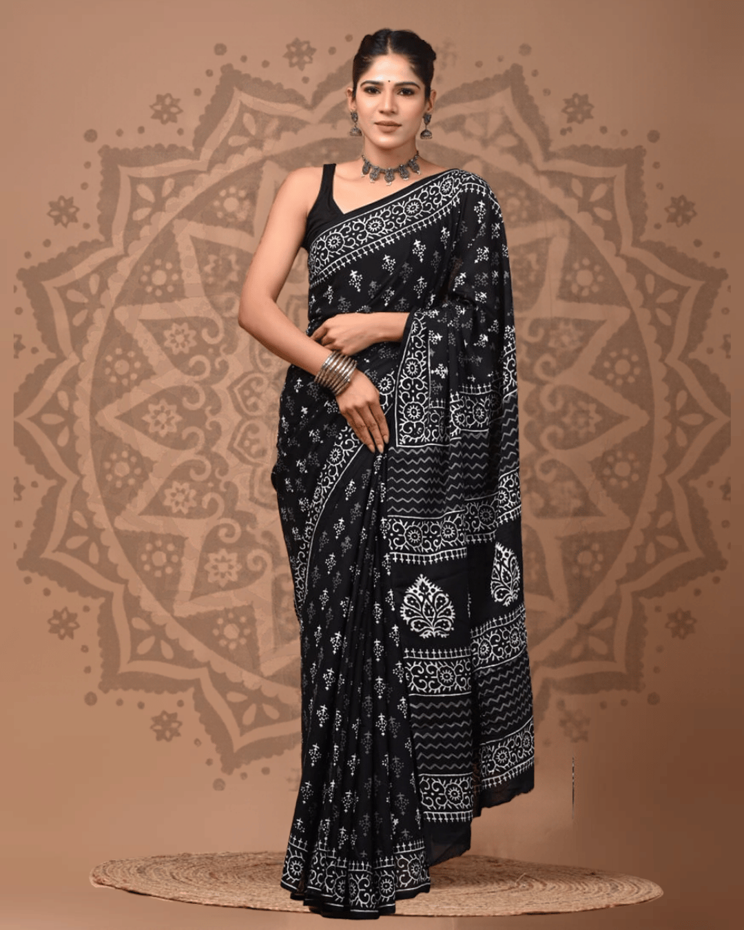 Black Mul Cotton ready-to-wear pocket saree with white floral motifs, a patterned border, zigzag bands and a pallu featuring bold ornamental leaf designs.