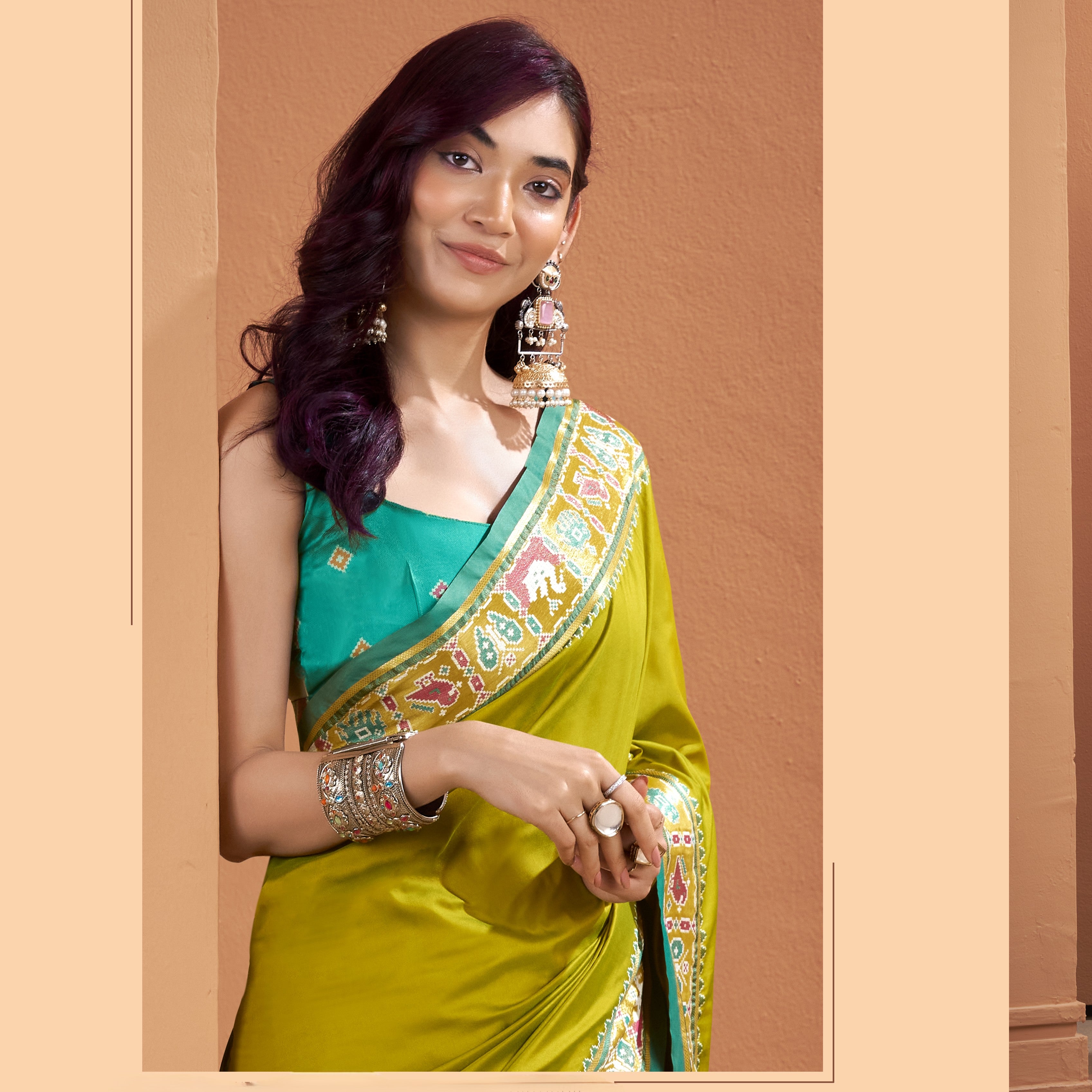 Close-up of olive yellow Patola Silk ready to wear saree with pocket showing its detailed teal, pink, cream and mustard geometric border