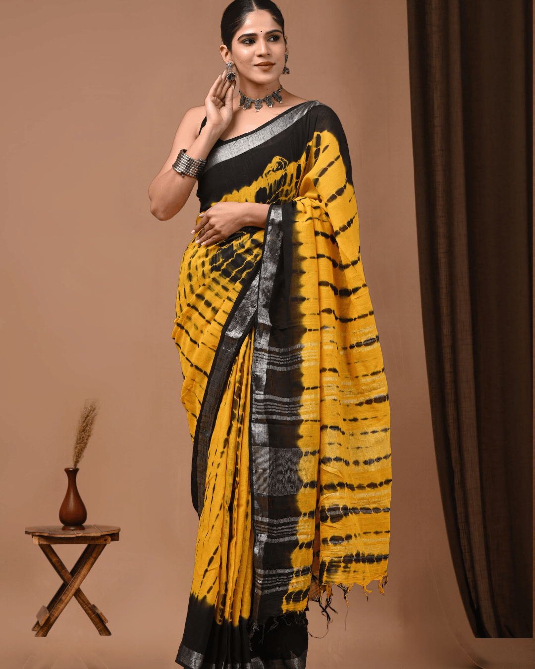 Mustard-yellow linen ready-to-wear pocket saree with irregular black tie-dye-inspired streaks, a solid black upper section, silver-grey borders, striped black pallu panel and tassels.