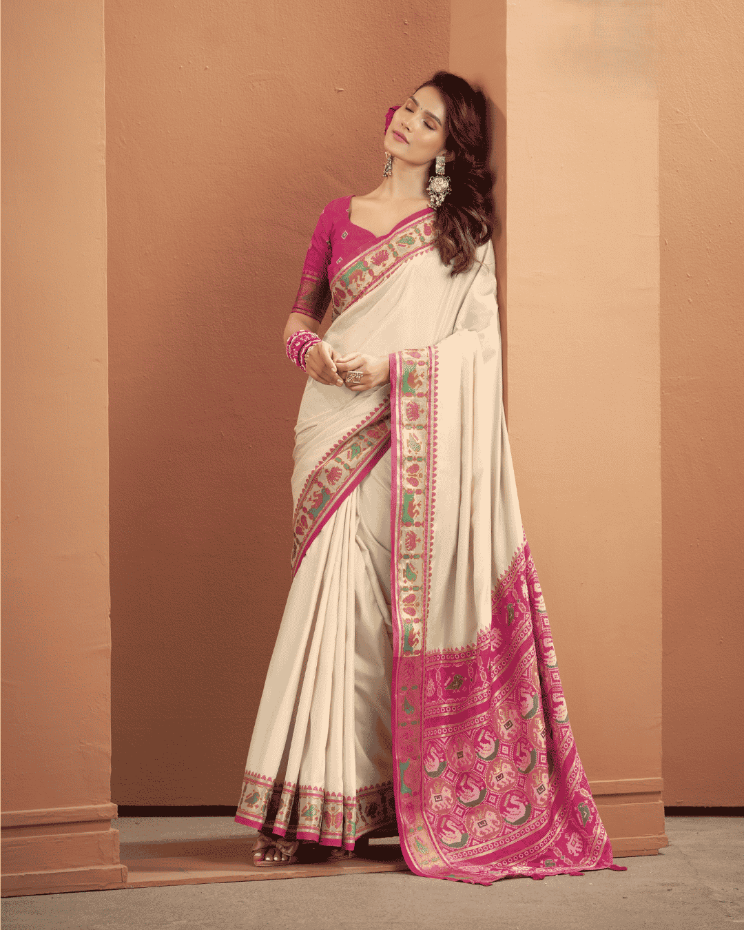 Full-length view of a model in an ivory Patola silk ready-to-wear pocket saree, showcasing the clean ivory drape, pink geometric Patola border, pre-stitched pleats, and an elaborate pink pallu with multicoloured woven motifs and tassels.