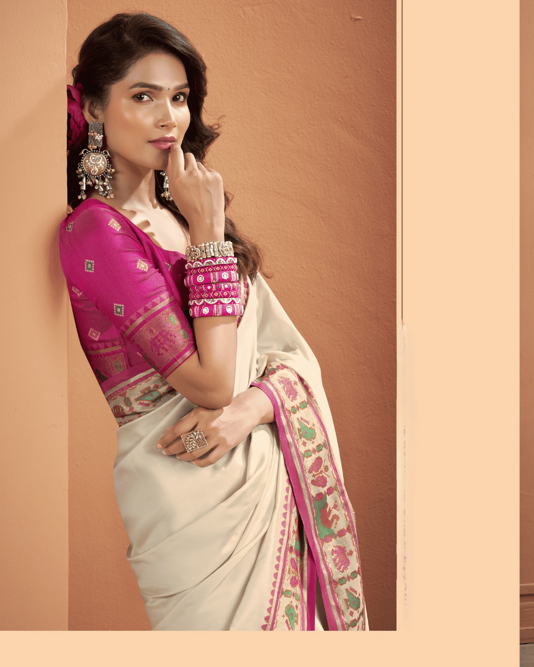 Medium close-up shot of a model wearing an ivory Patola silk ready-to-wear pocket saree, featuring a pink-edged border woven with colourful geometric Patola motifs.