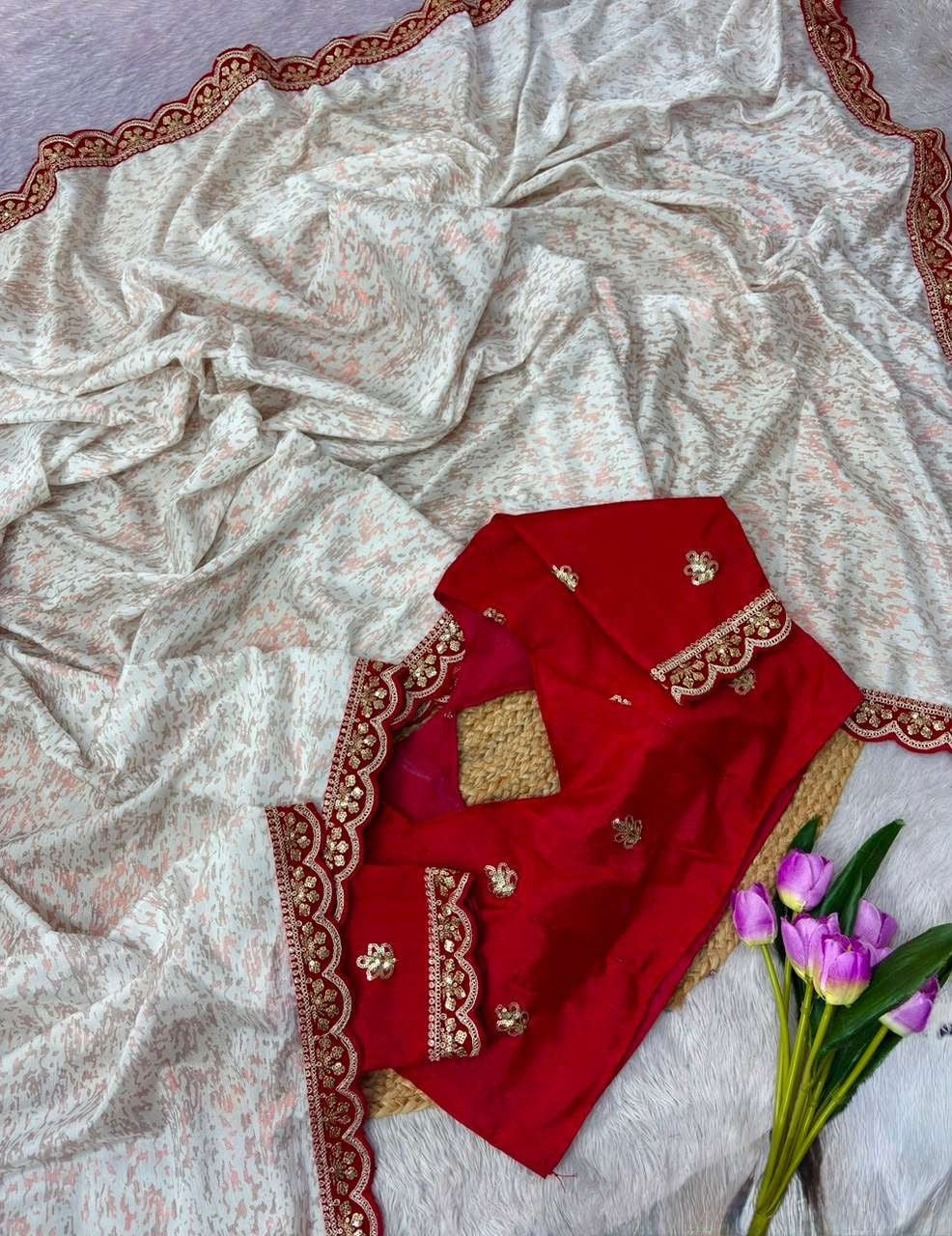 Flat-lay detail shot of the Dola Silk saree showcasing a soft ivory base with subtle peach micro-patterns, featuring a rich crimson red scalloped border with intricate gold floral embroidery.