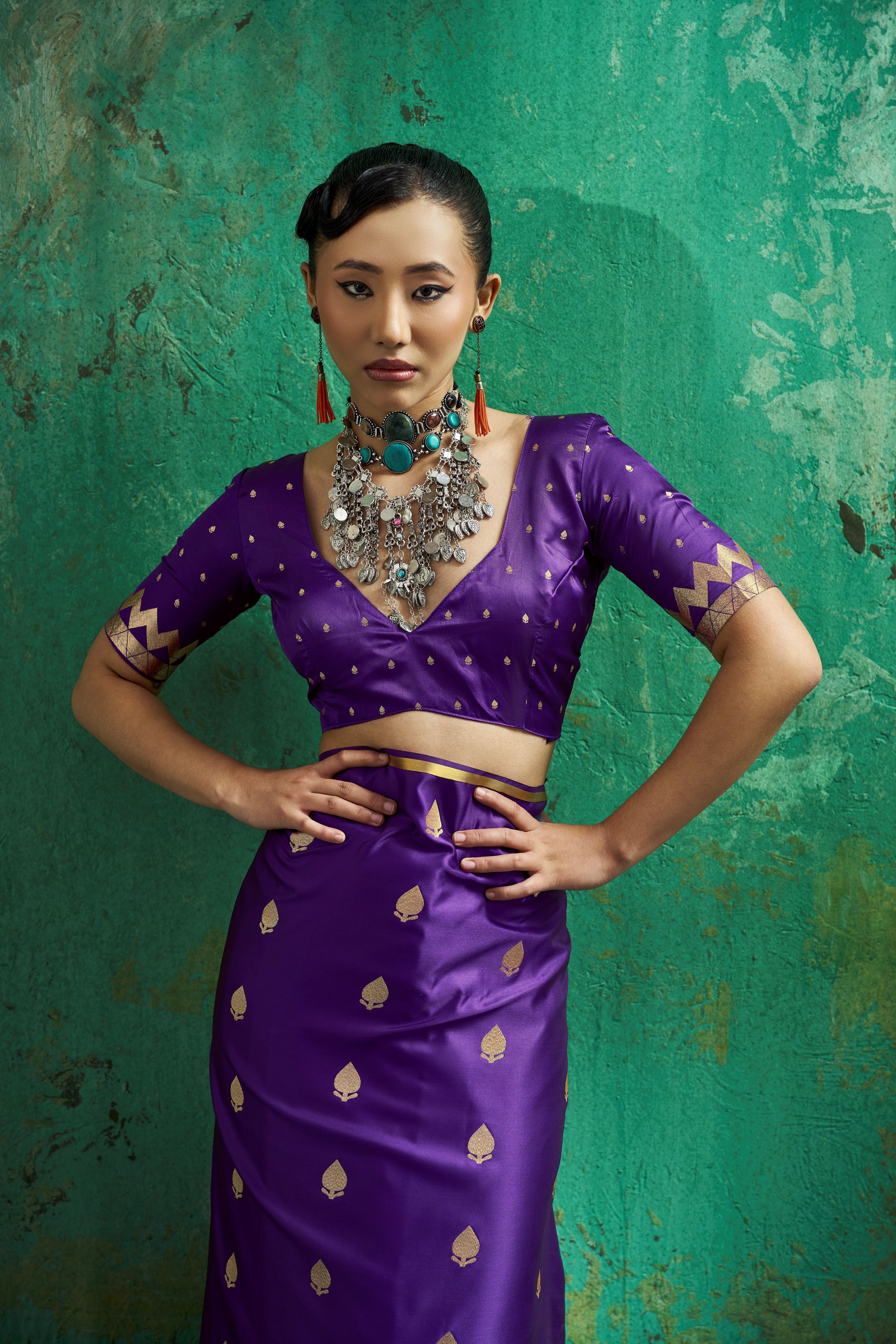 Model posing in a deep V-neck blouse with gold zari chevron embroidery styled with a rich purple satin 15 second pocket saree.