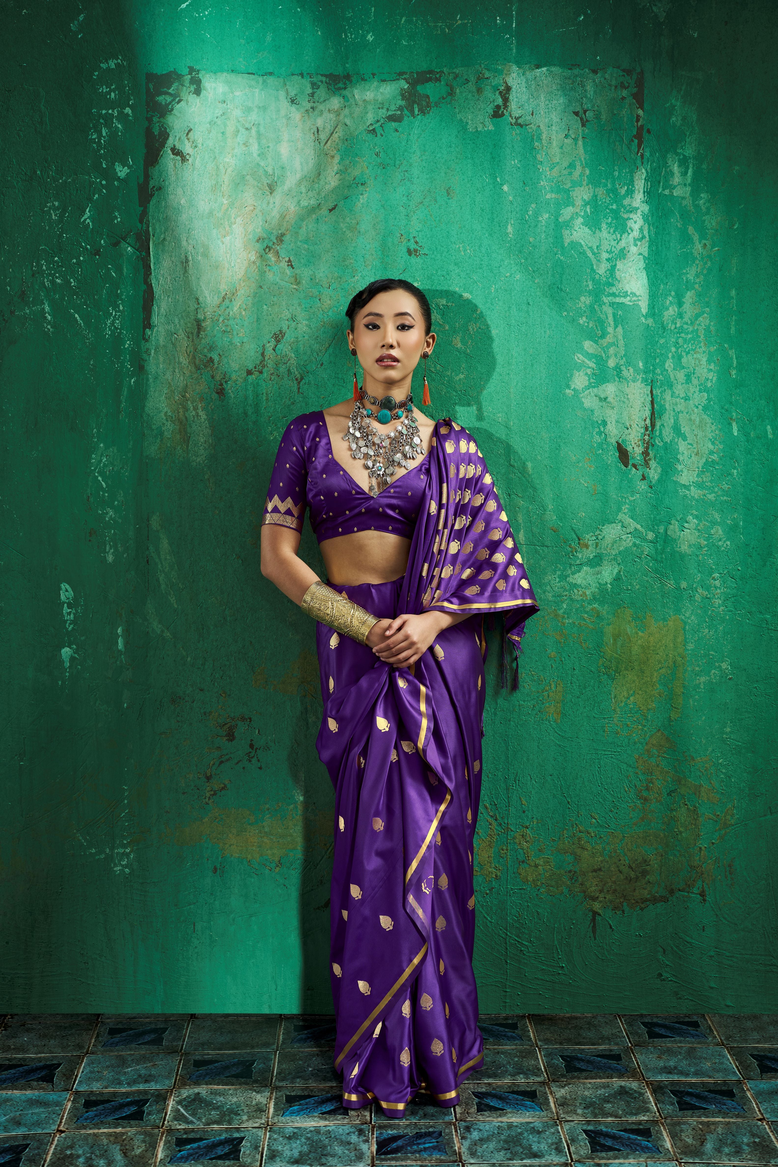 Full-length view of a model in a ready to wear pocket saree in vibrant royal purple satin with pre-stitched pleats and golden borders.