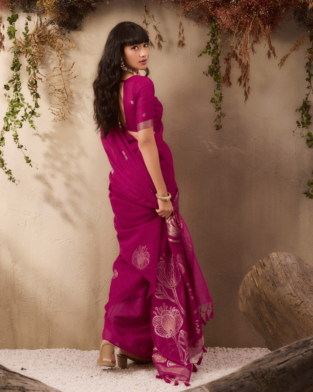 Back view of the model, showcasing the smooth silk drape and delicate tassel finish at the edge of the pallu.