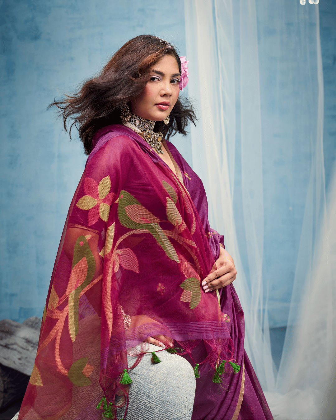 Close-up shot focusing on the sheer pallu, detailed with olive green, pink, and yellow woven leaf motifs and tiny green tassel trim.