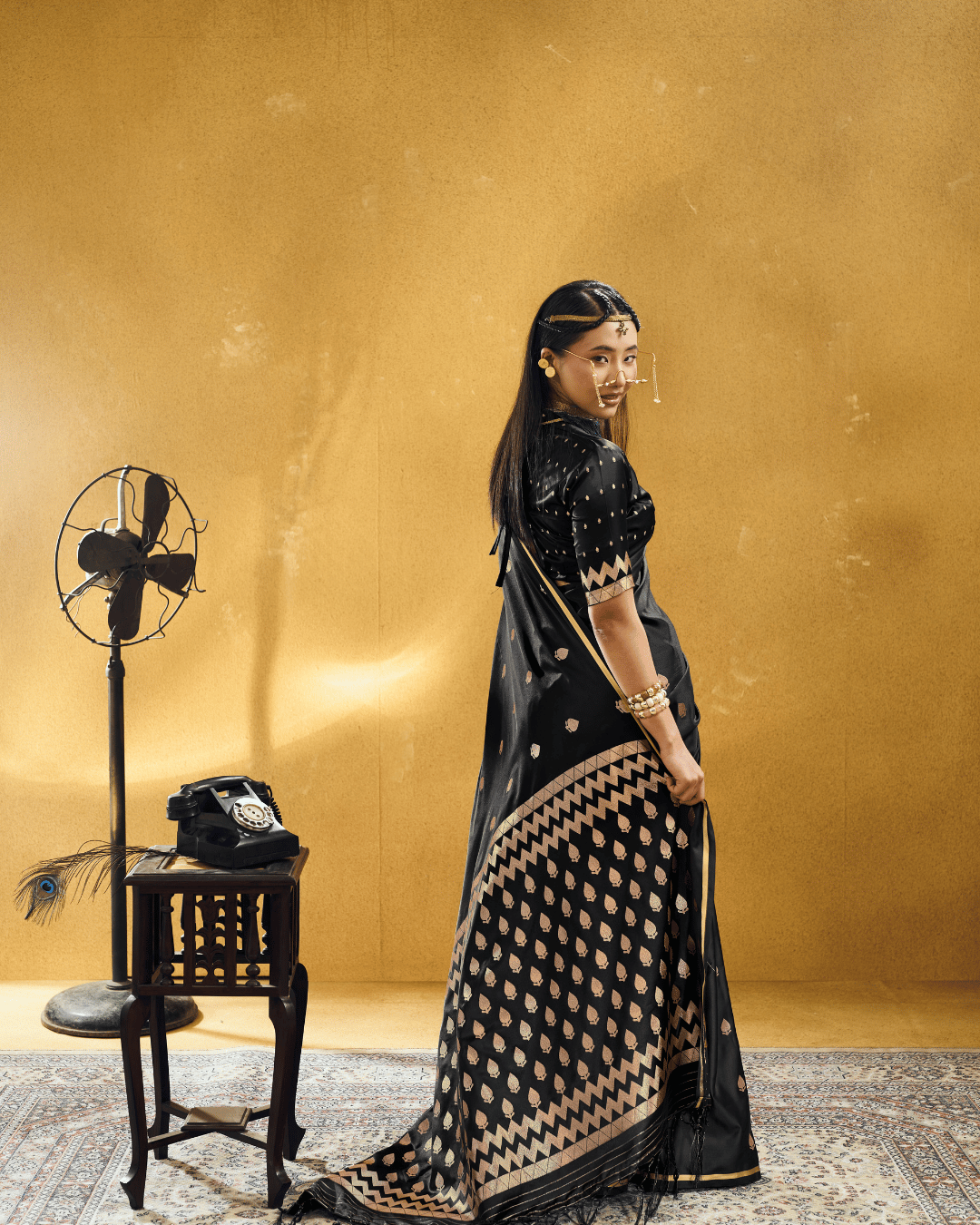 Back-angle full-length view highlighting the grand graphic pallu of the Black Chevron powerloom silk ready-to-wear pocket saree, displaying dense rows of woven champagne-gold leafy motifs framed by multi-tiered chevron bands and black edge tassels.