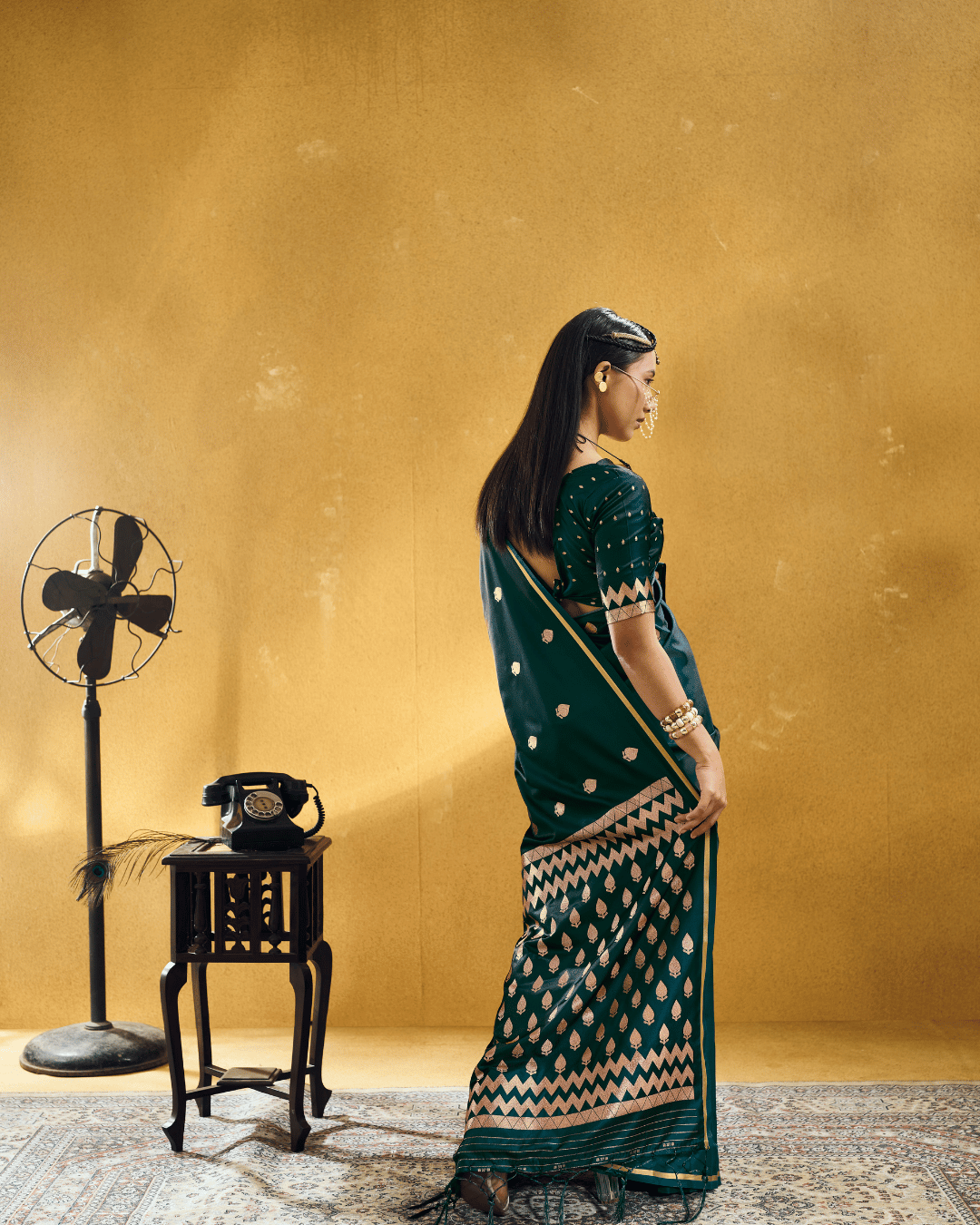 Full-length back-angle view showcasing the grand graphic pallu of the Forest Green Chevron ready-to-wear pocket saree, adorned with dense rows of gold leaf motifs enclosed by multi-tiered zigzag chevron bands and matching green tassels.