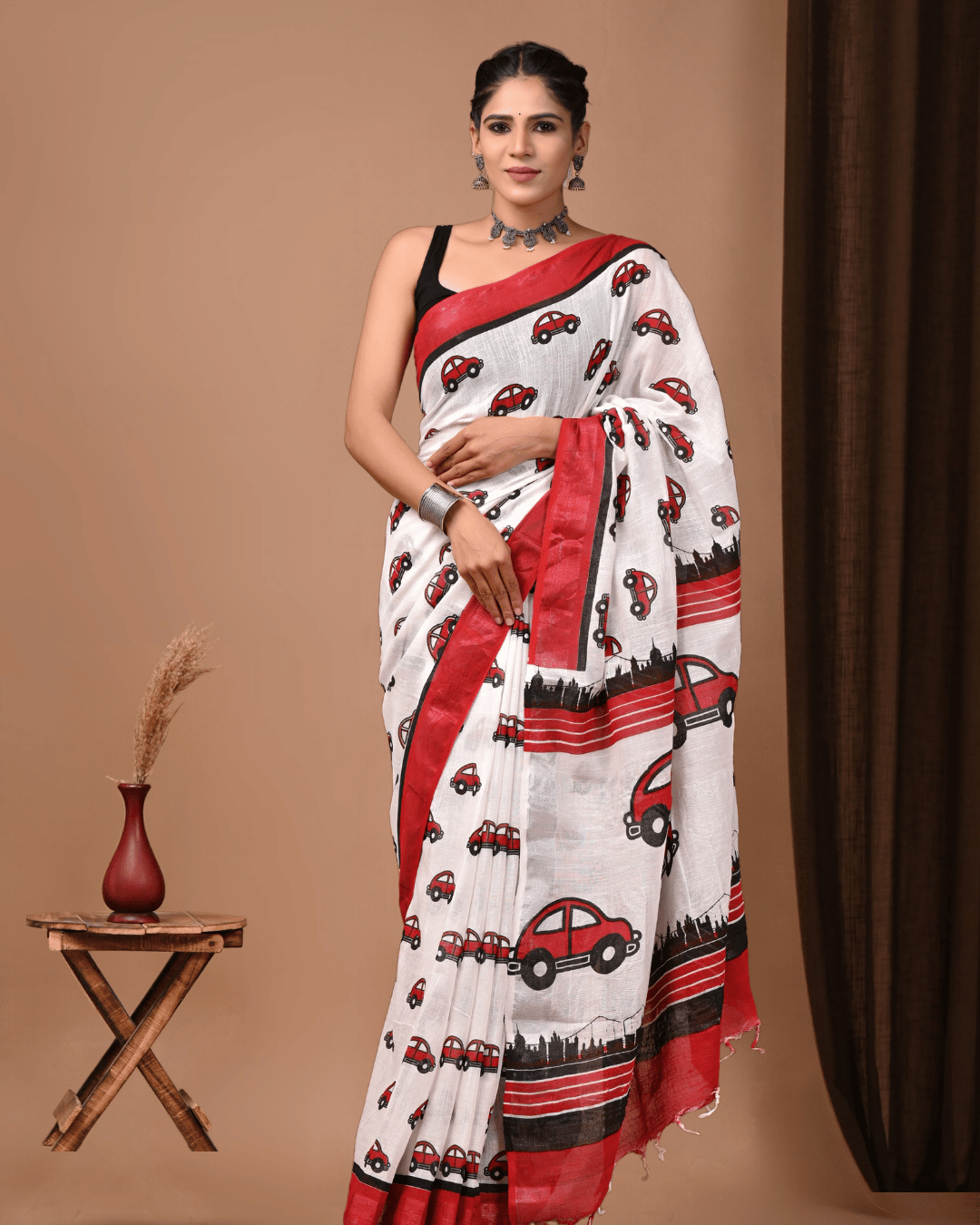 Ivory-white linen ready-to-wear pocket saree with scattered red cars outlined in black, a red border, black cityscape silhouette, striped pallu and tassel finish.