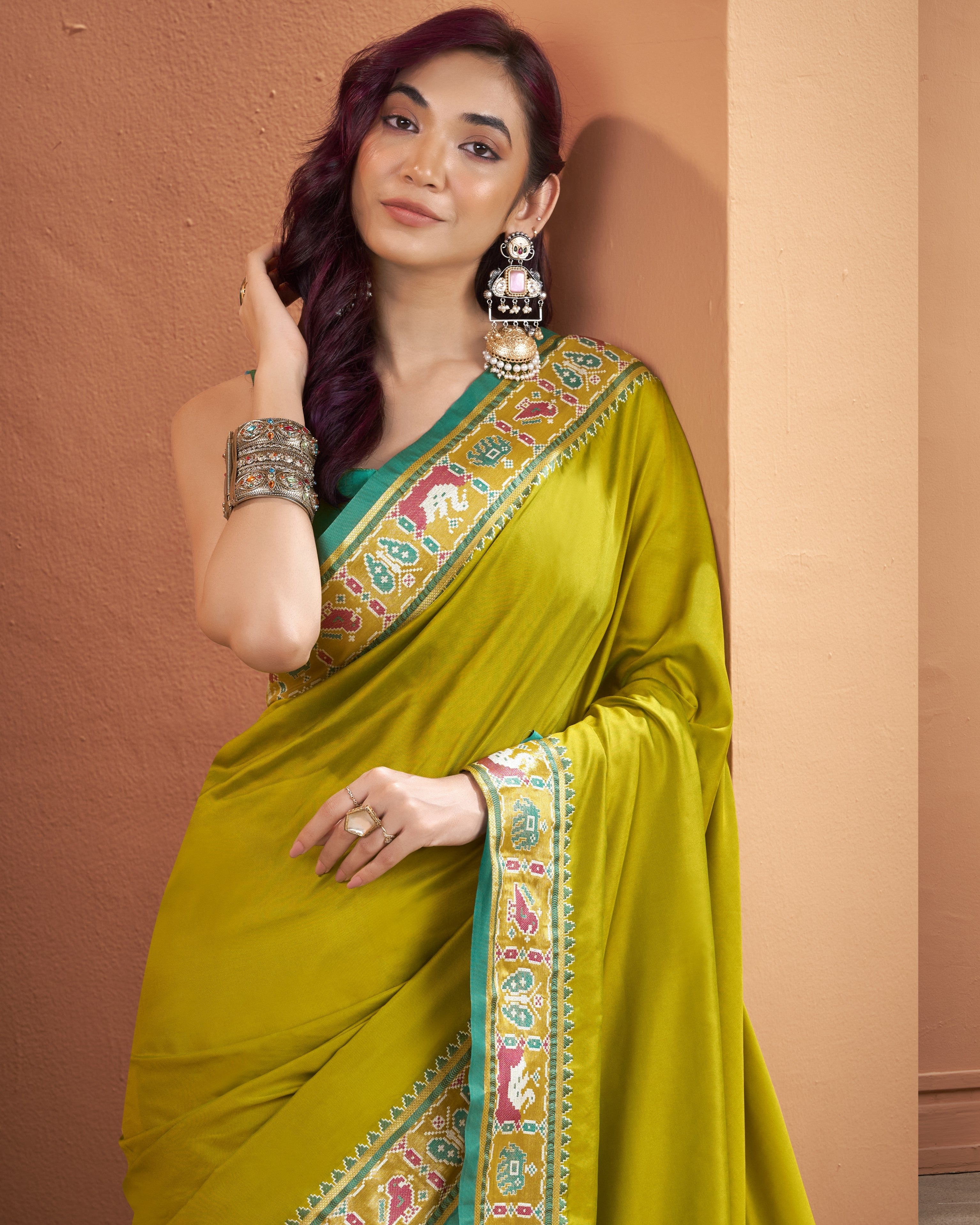Model wearing an olive yellow Patola Silk ready to wear pocket saree with a detailed multicoloured border