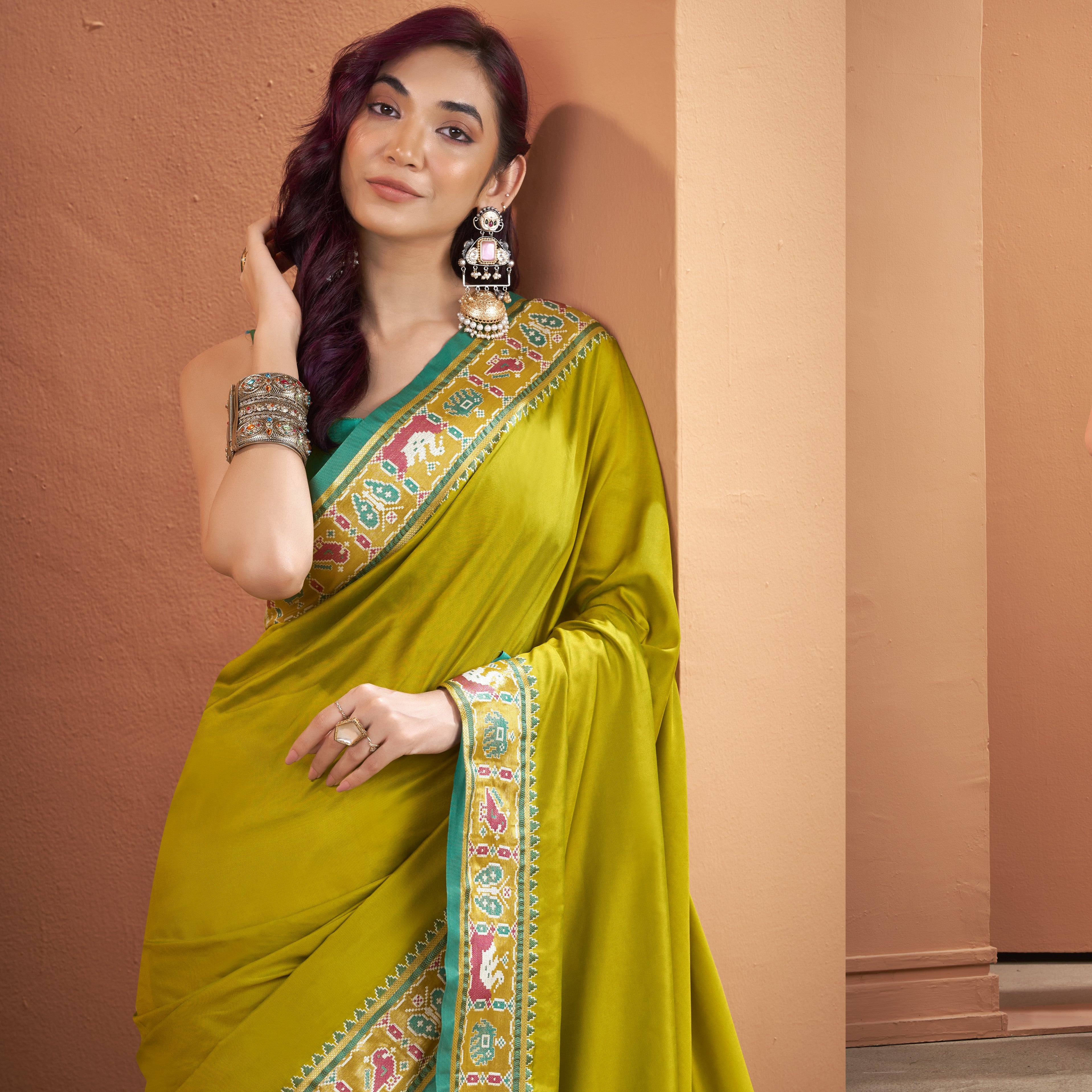 Model wearing an olive yellow Patola Silk ready to wear pocket saree with a detailed multicoloured border