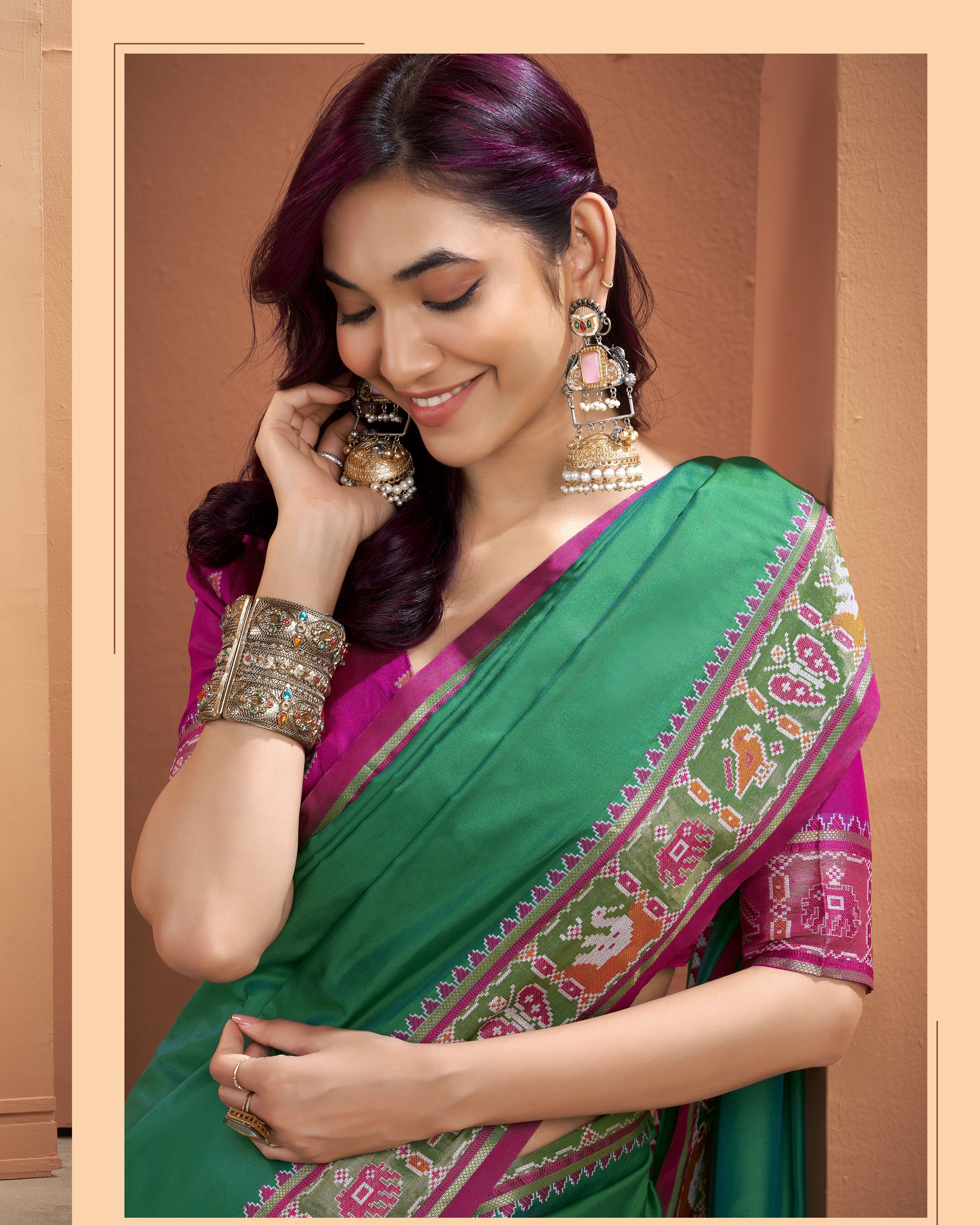 Close-up view of the green Patola silk pre-draped pocket saree highlighting the geometric patterned border, magenta detailing, and smooth silk fabric
