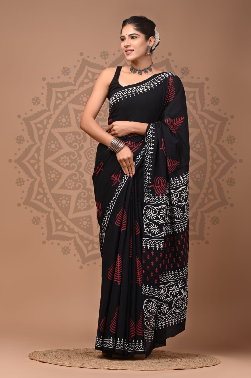 Full-length portrait of a model in a deep jet-black Mul Cotton ready-to-wear pocket saree, featuring slender crimson red leaf motifs, pre-stitched pleats, and crisp ivory-white printed geometric and floral borders.