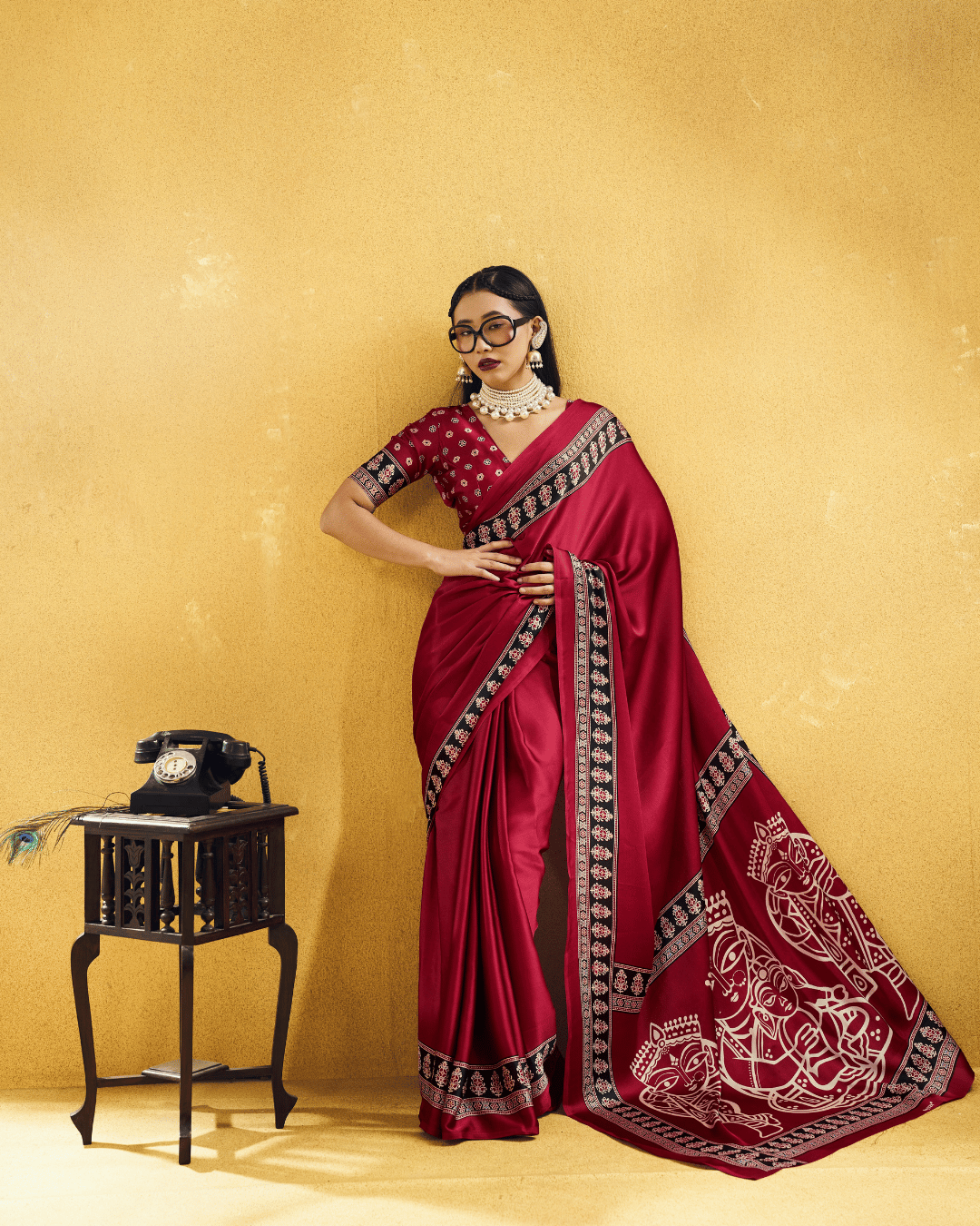 Full-length portrait of a model in a deep wine saree, highlighting the smooth drape, patterned black border, and statement graphic pallu.