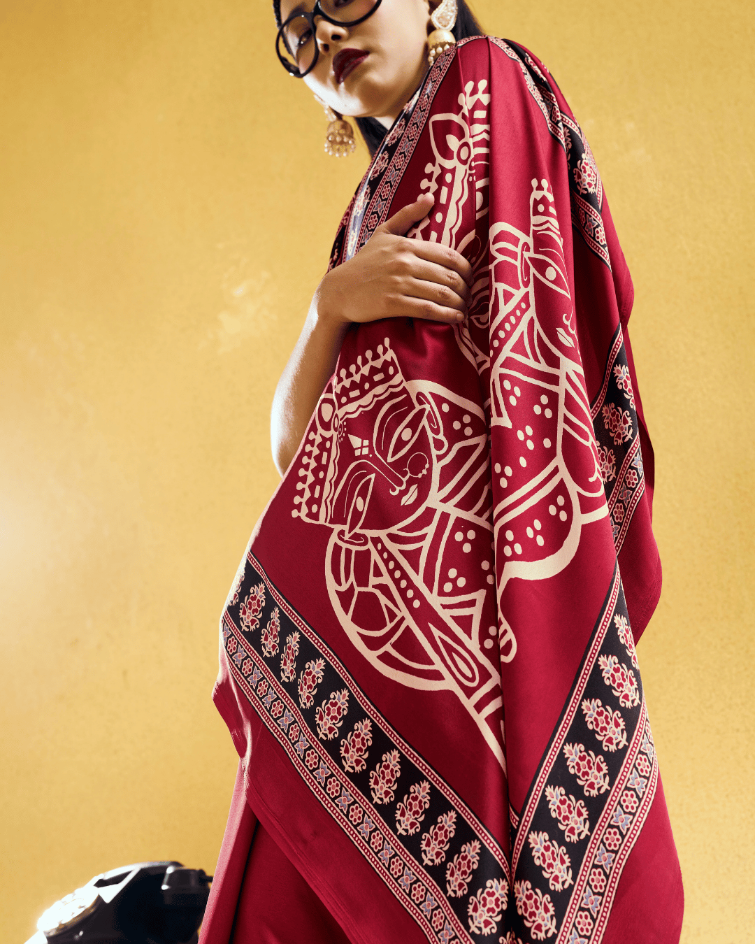 Close-up of the pallu showing detailed ivory figurative artwork framed by intricate black and ornamental printed borders.
