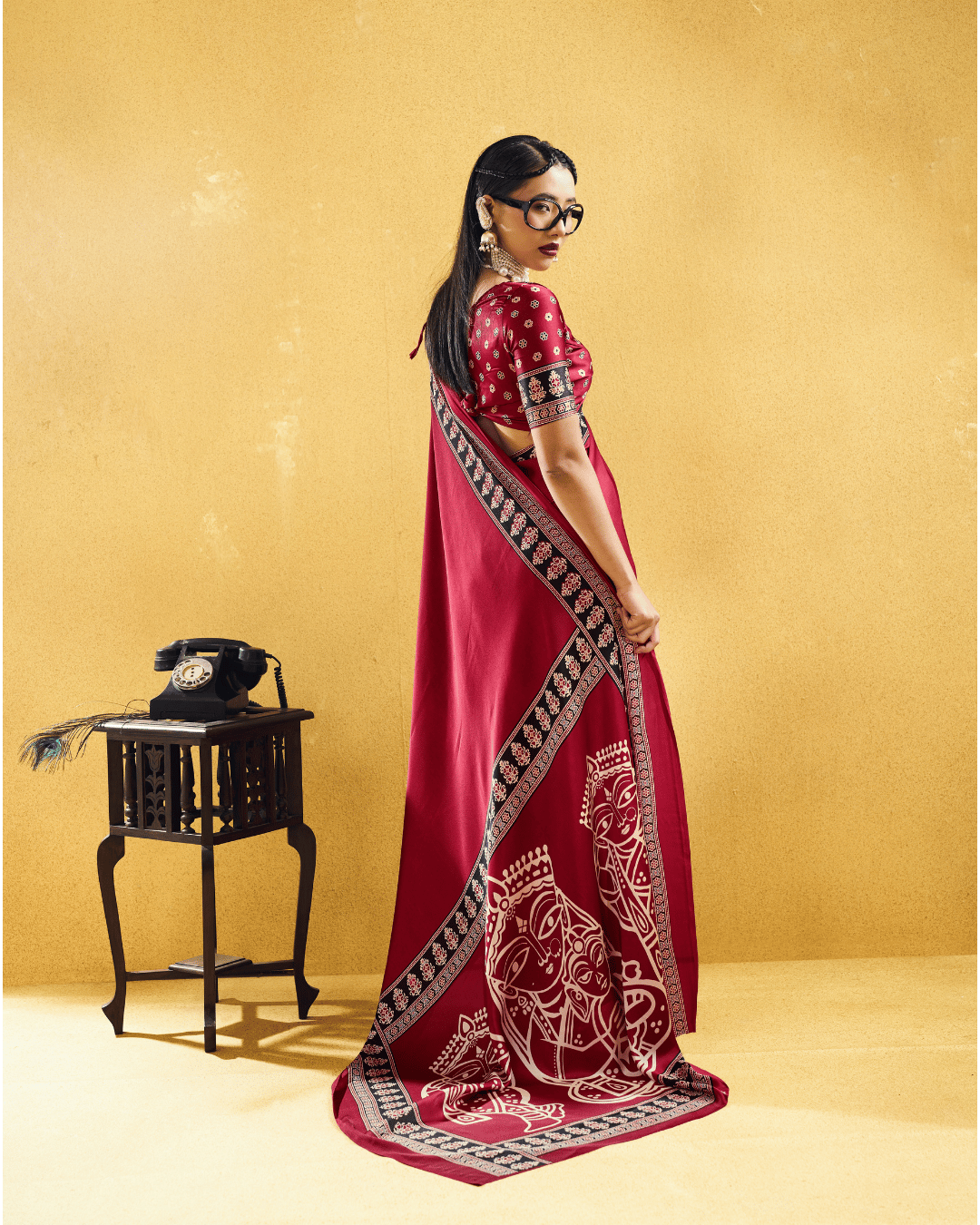 Back view of the wine saree displaying the elegant fall of the pallu with traditional ivory motifs and patterned trim.