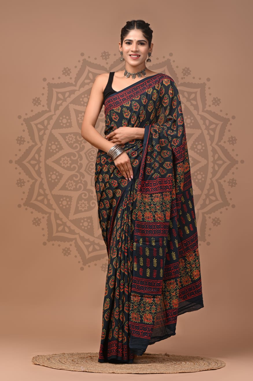 Full-length portrait of a model wearing a deep green Mul Cotton ready-to-wear pocket saree, featuring all-over red, mustard, and green floral-leaf motifs, pre-stitched pleats, and a layered block-printed pallu.