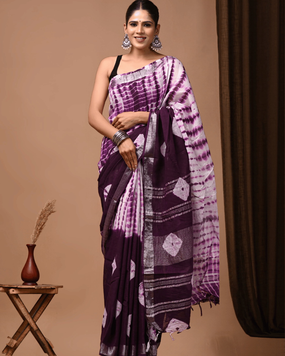 Dye in Motion plum and lilac linen ready-to-wear pocket saree with irregular purple tie-dye-inspired streaks, a deep plum panel, pale diamond-like motifs, silver-grey stripes and dark tassels.