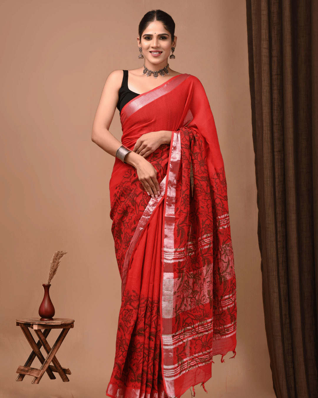 Flora Script a Red linen ready-to-wear pocket saree with black outlined floral motifs, a plain red upper section, silver-grey border, striped pallu and red tassels.