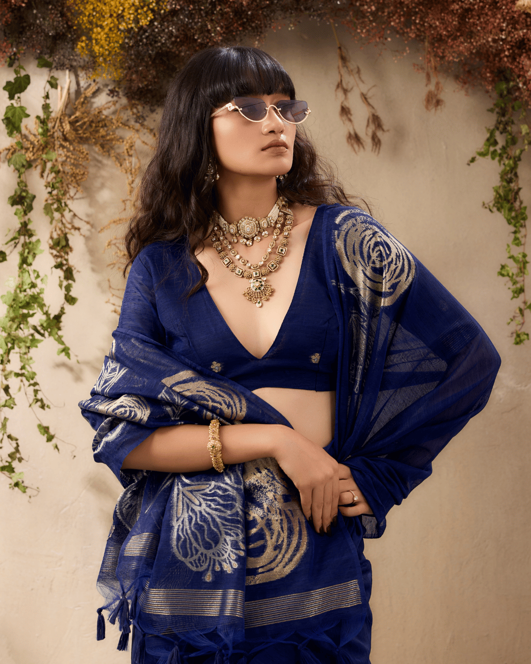 Wrapped pallu of the vine and verse ready to wear pocket saree in navy blue to emphasize the shimmering gold line art, fine striped hem, and tassel details.