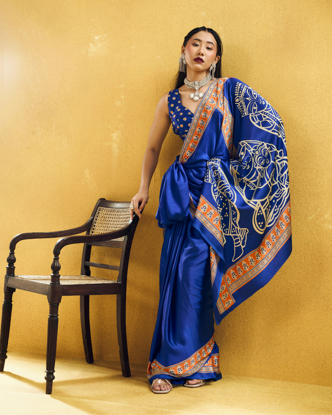 Full-length portrait of a model in a royal blue ready-to-wear saree with an intricate orange border and statement open pallu.