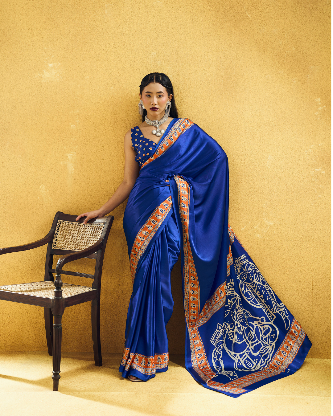 Model posing in a deep royal blue ready to wear pocket saree with a statement folk art pallu and contrasting orange border.