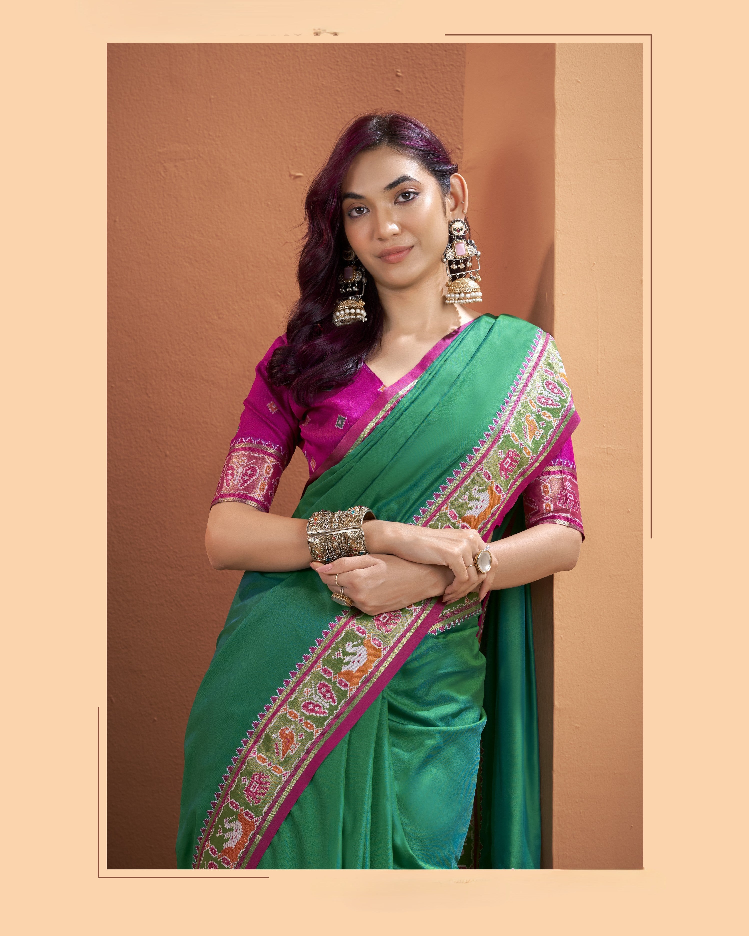 Close-up of the green Patola silk pre-draped saree with pocket showing its detailed multicoloured patterned border and contrasting pink accents.