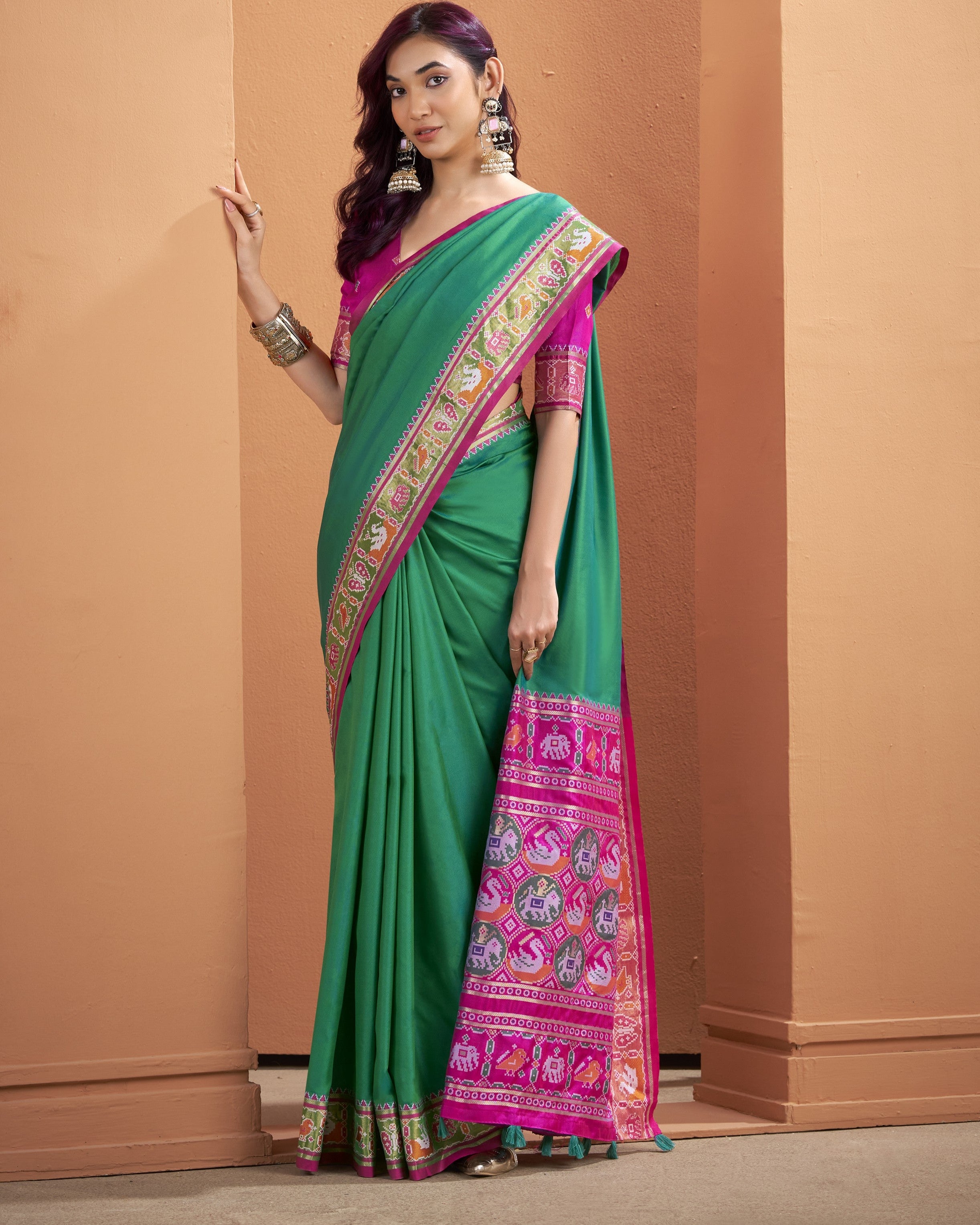 Full-length view of the green Patola silk ready-to-wear pocket saree with a broad magenta patterned pallu finished with green tassels.