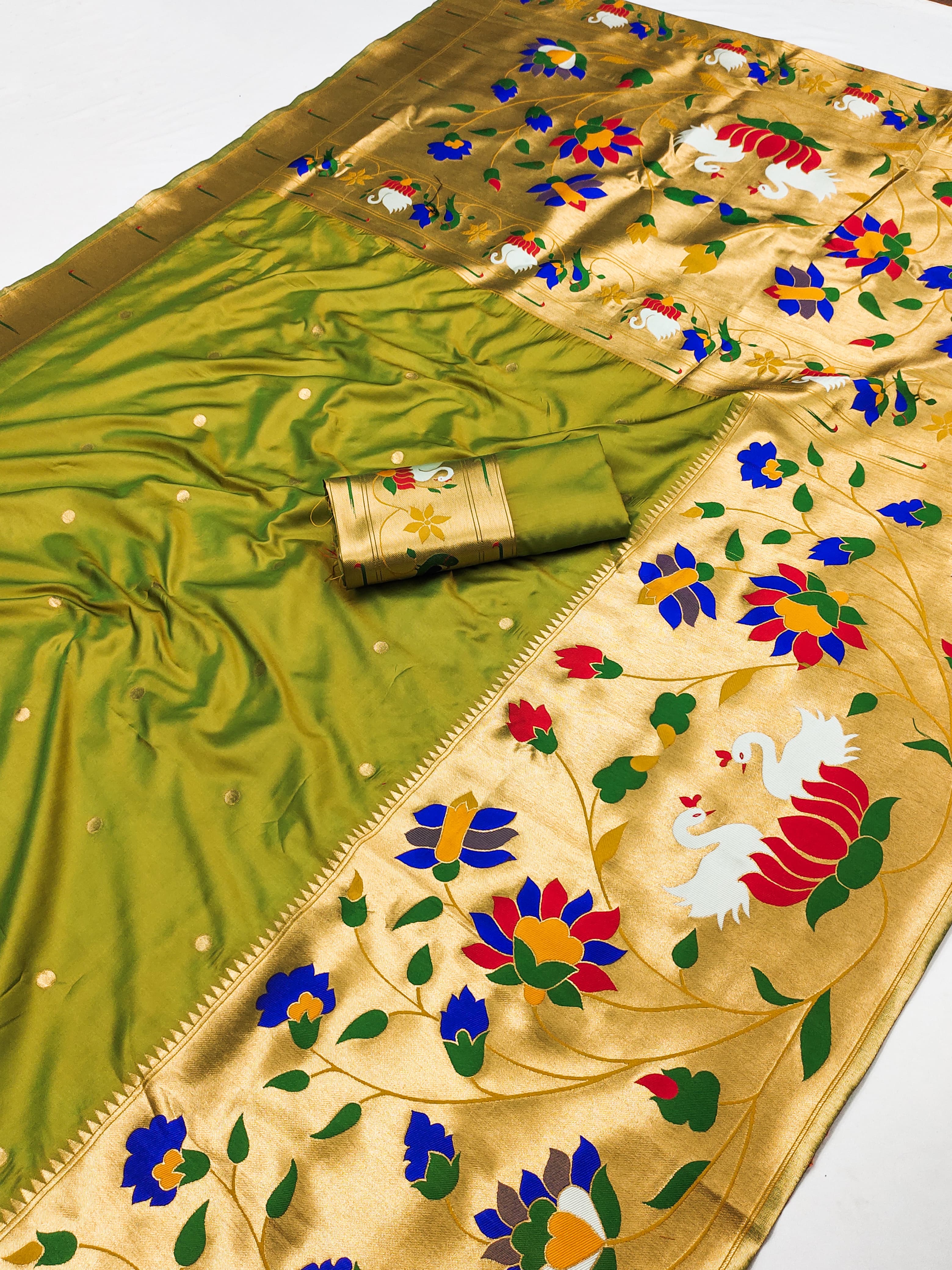 Flat lay of a mehendi green Paithani silk saree displaying small golden boti dots, a broad gold border, and a vibrant golden pallu woven with flowers and swan motifs.