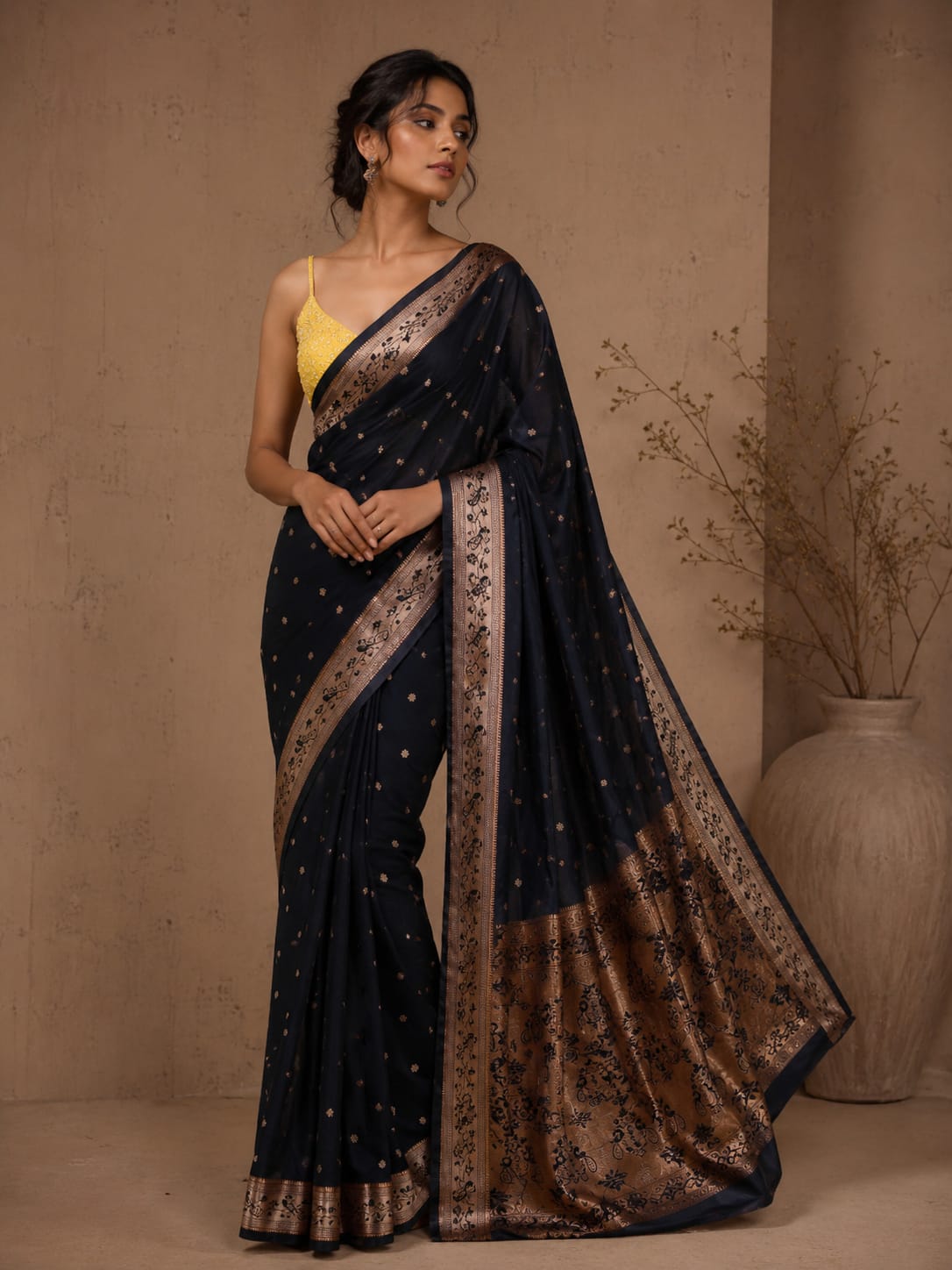 Full-length portrait of a model wearing the ruhani deep black Powerloom Silk ready-to-wear pocket saree, featuring scattered antique gold buta motifs, a floral-vine border, and an ornate antique-toned paisley pallu.