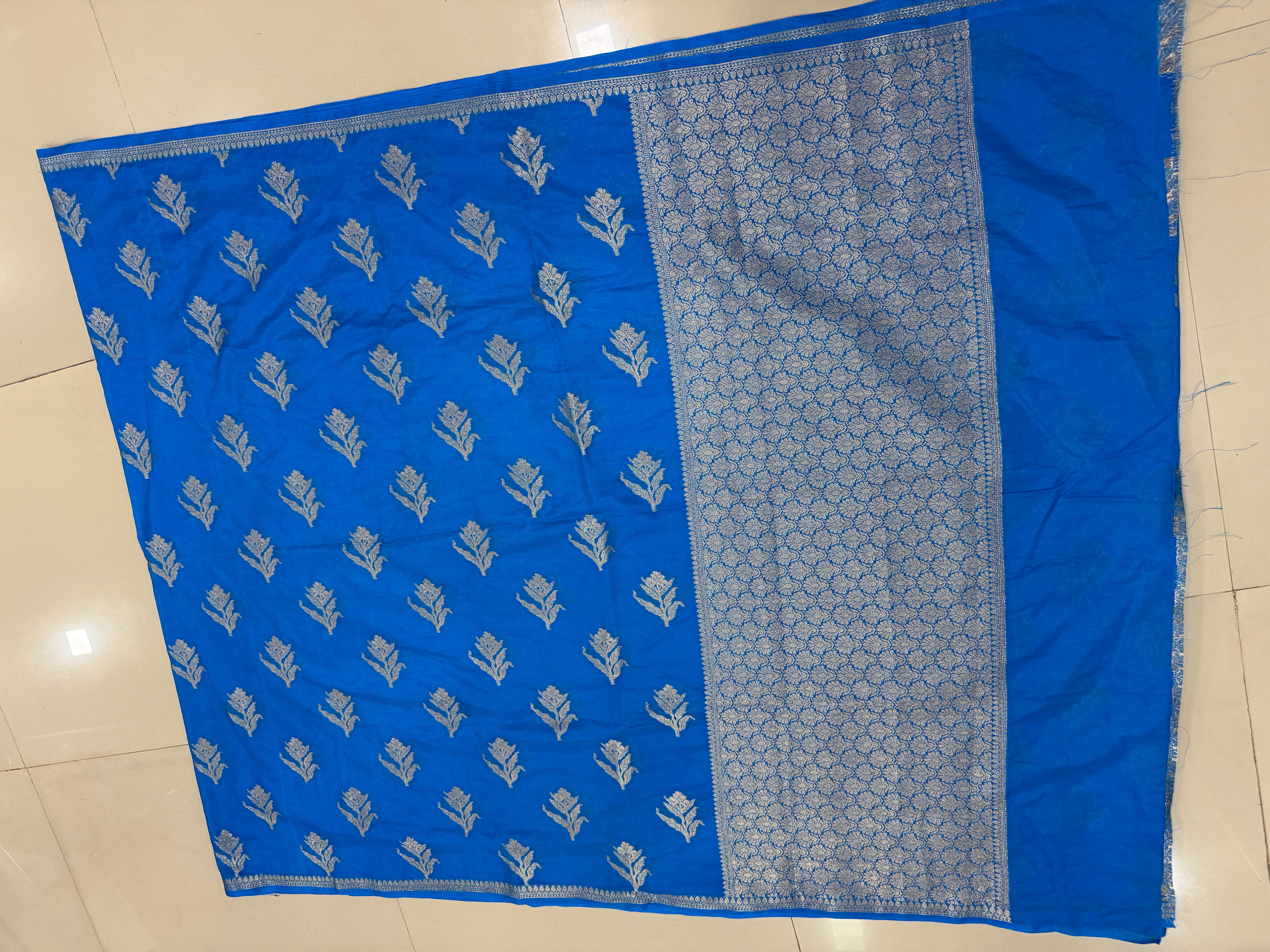 Flat lay view of the bright blue Banarasi Katan Silk pre-draped pocket saree, displaying the scattered zari floral-bud motifs across the body and the broad woven zari lattice pallu panel framed by fine linear borders.