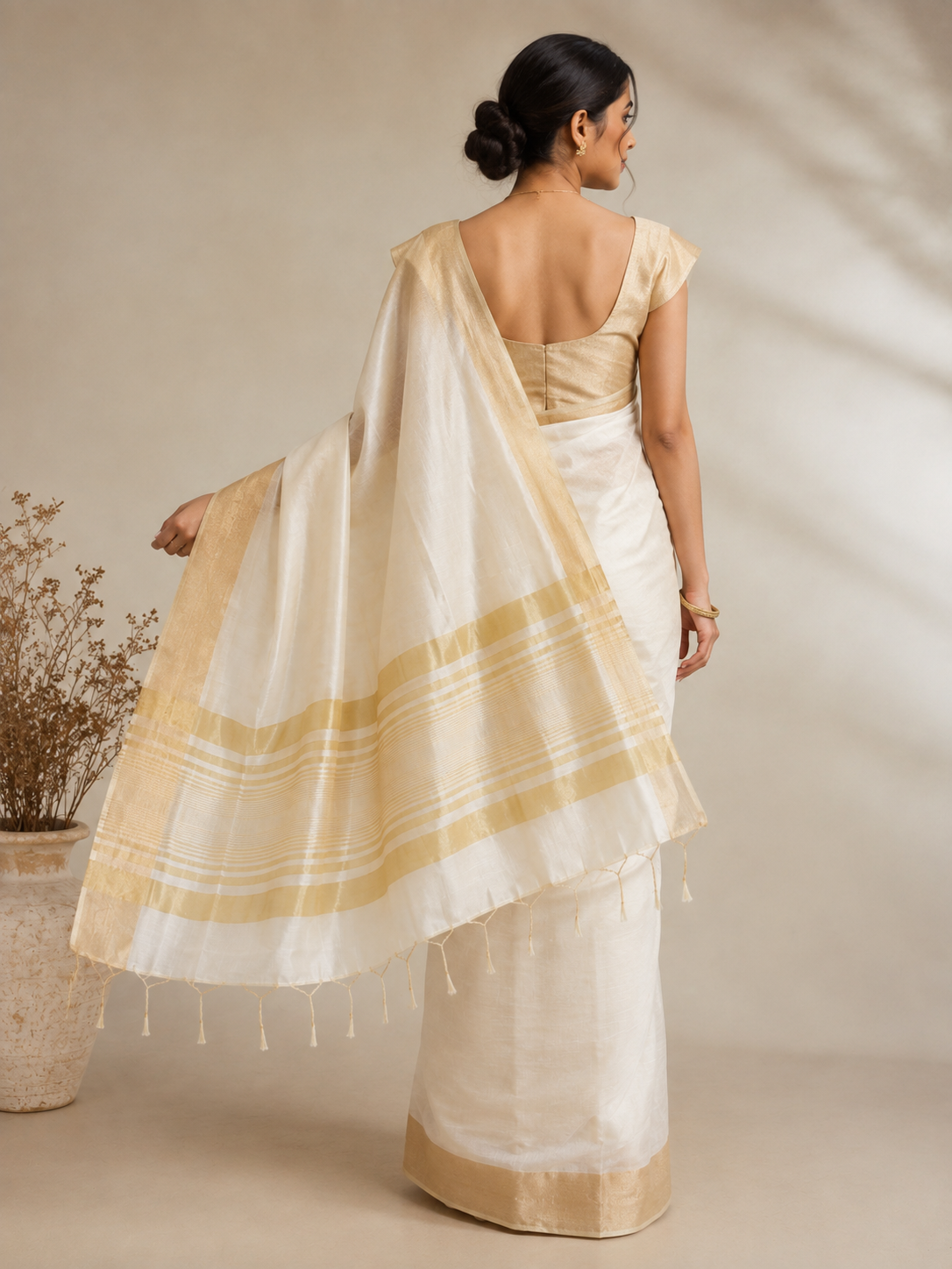 Back view of an ivory Silk Cotton ready to wear pocket saree with a soft-gold zari border and detailed striped pallu finished with delicate golden tassels.