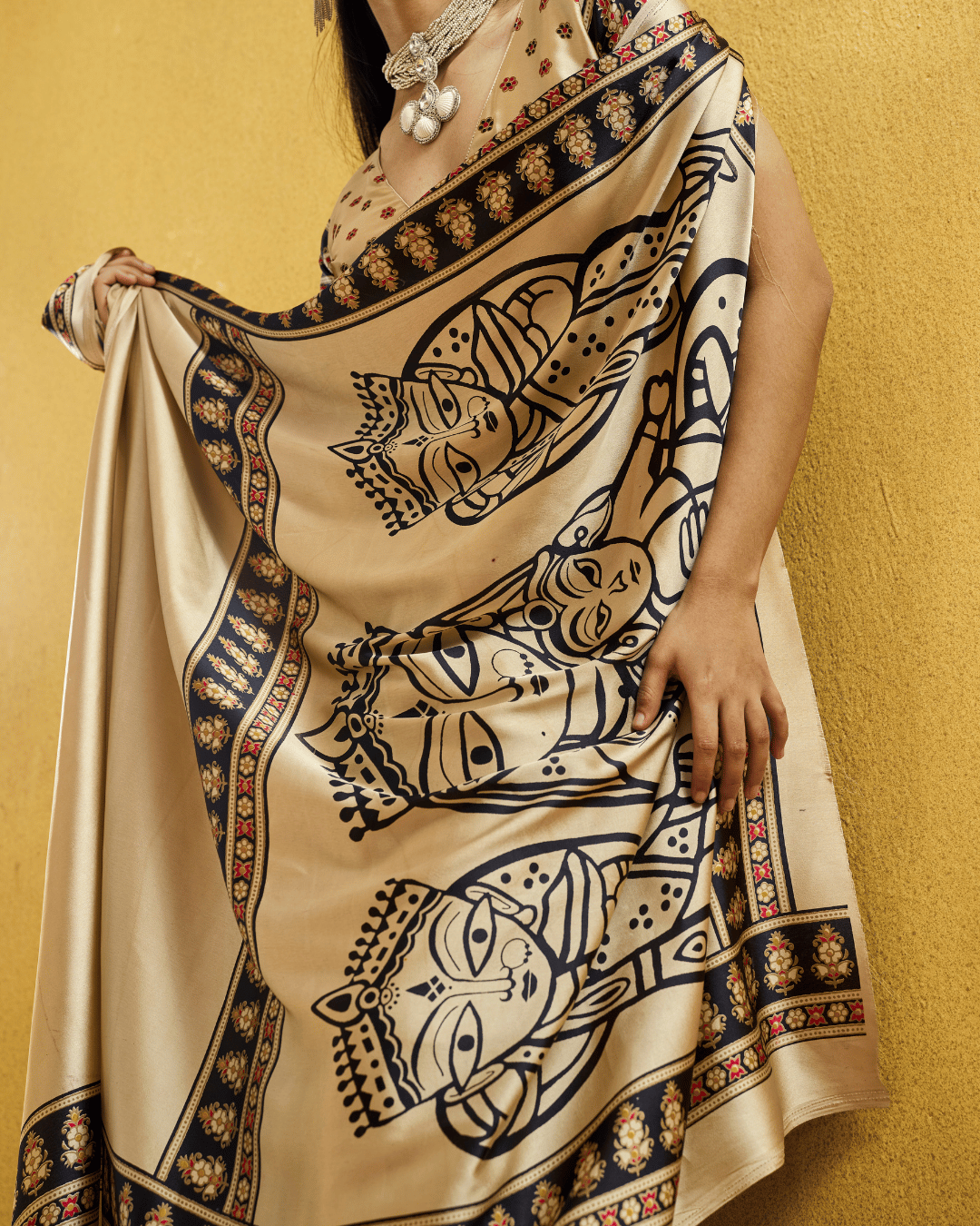 Close-up shot of the soft ivory-beige saree highlighting the large navy figurative pallu motifs and intricate printed border.