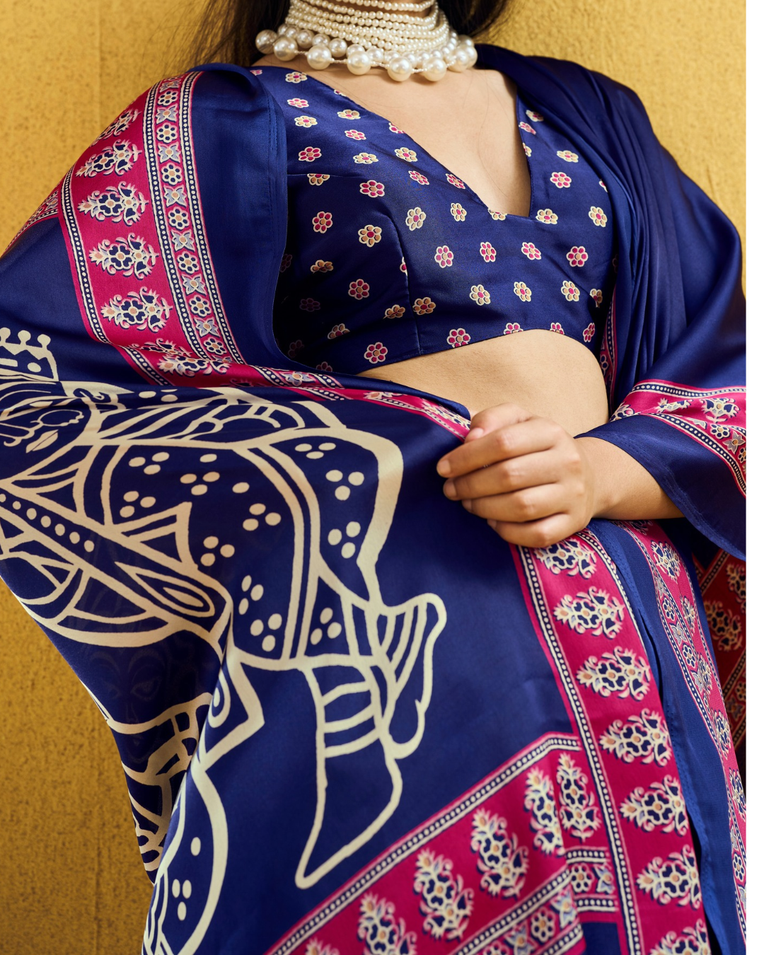 Close-up shot of the navy saree showing intricate magenta border patterns and ivory folk-art pallu prints.