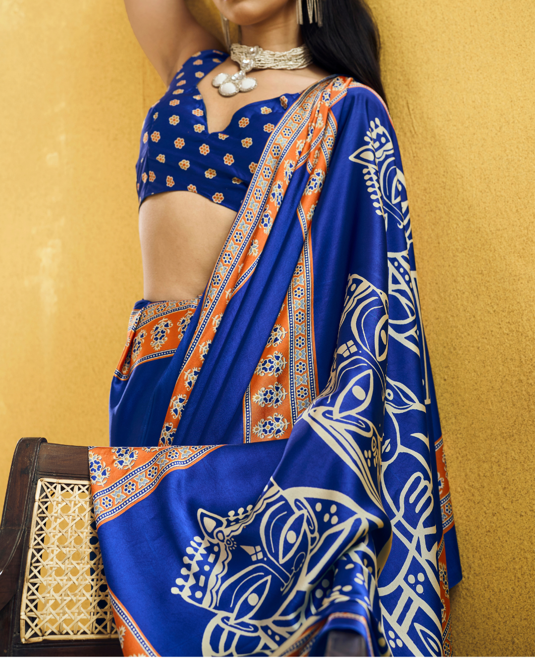 Detailed close-up showing the vivid orange patterned border and large ivory folk-art pallu artwork of the rich royal blue pre-draped pocket saree.