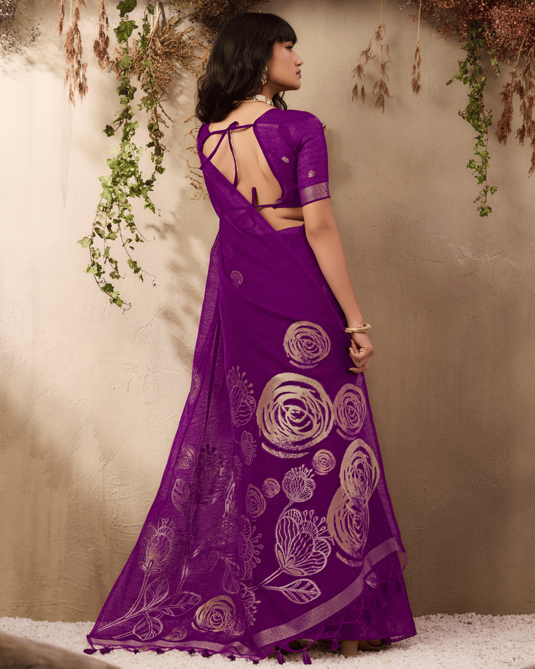 Full back view showing the wide spread of the deep purple pallu featuring oversized circular rose-like motifs and botanical sketch patterns and matching purple tassels.