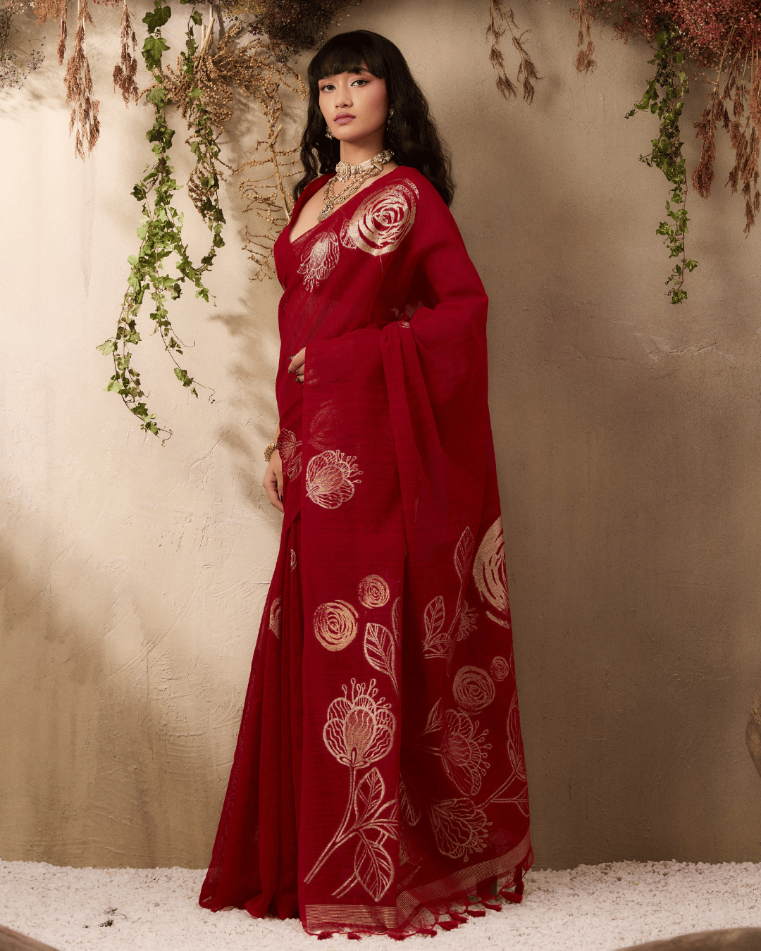 Model posing at a three-quarter angle in the ruby-red ready-to-wear pocket saree, highlighting the gold rose-and-leaf motifs.