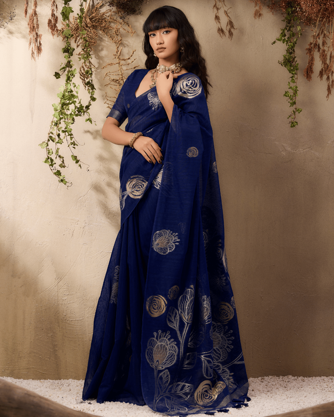 Model standing at a slight angle in the navy blue pocket saree, highlighting the fluid fall of the silk-blend fabric and the bold botanical line-art motifs extending down the pallu.