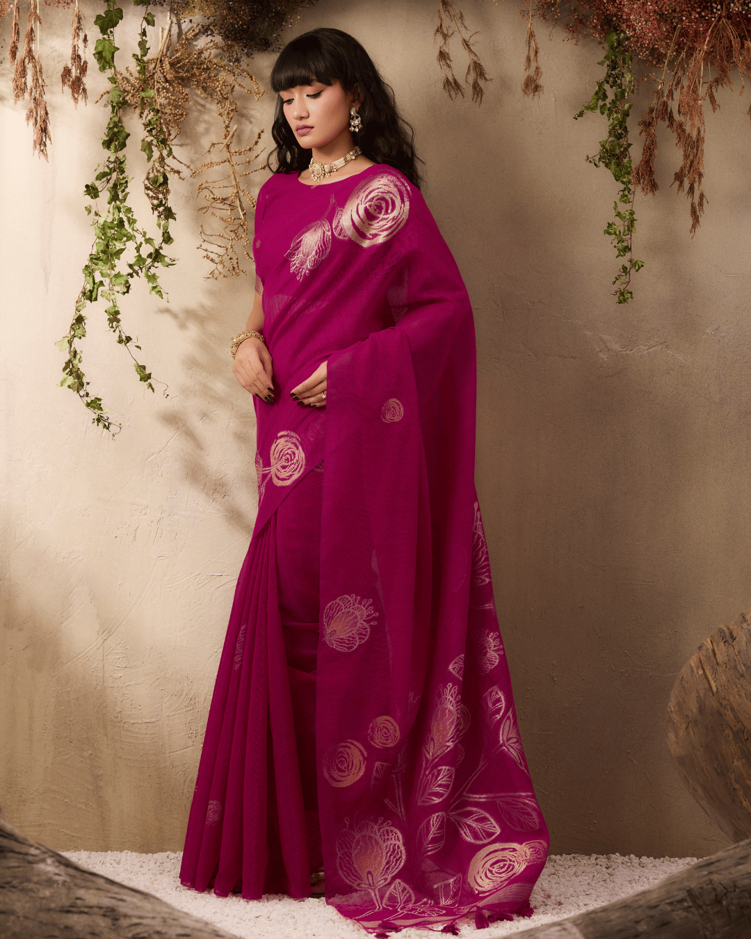 Model displaying the gold rose-like blooms and leafy stems across the front and lower pallu of the vine and verse pre-draped pocket saree.